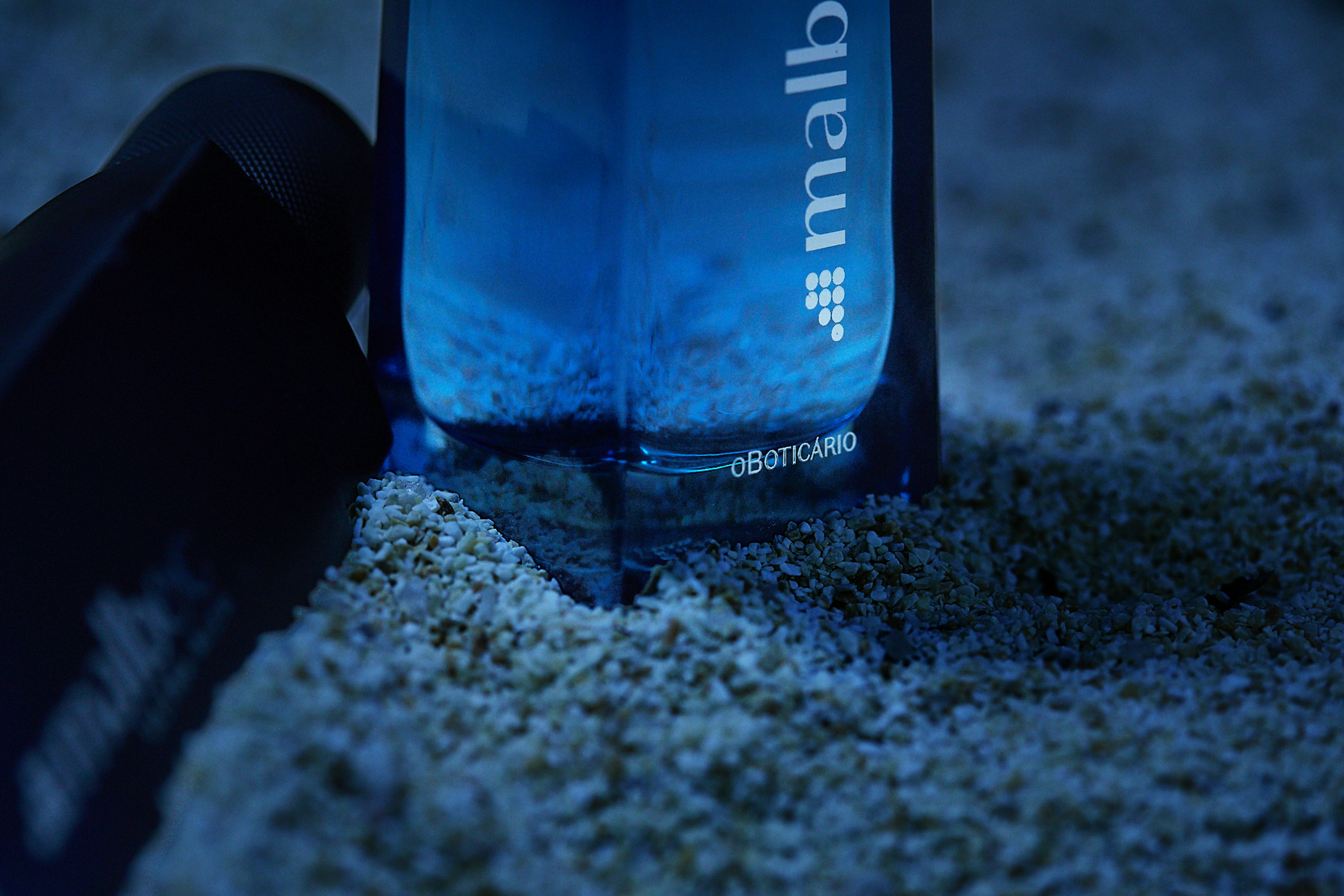 Processo de criação da fotografia do dois frascos do perfume Malbec Bleu do o Boticário em cima de uma tora de madeira na areia da praia de noite