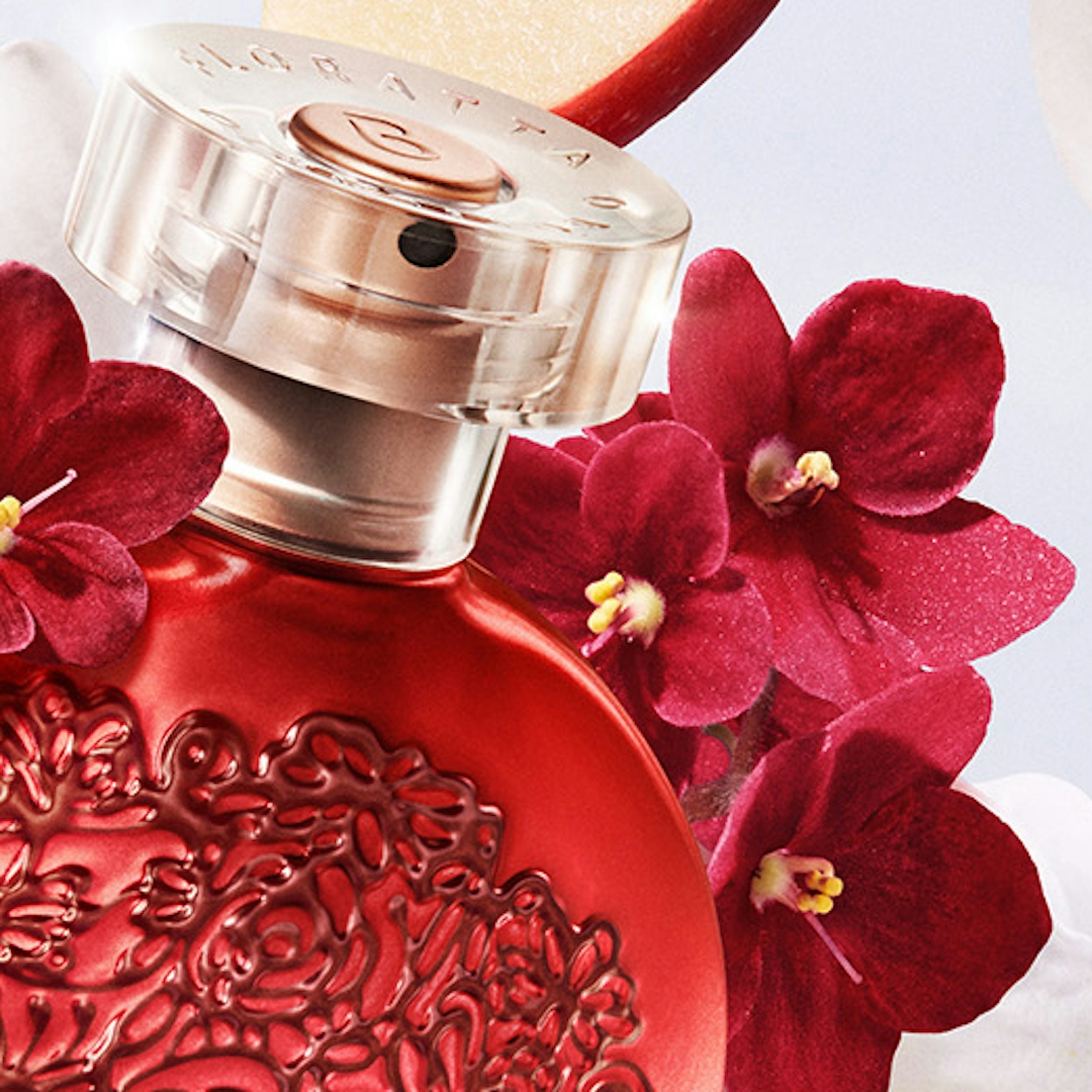 Um close de um frasco de perfume com flores vermelhas