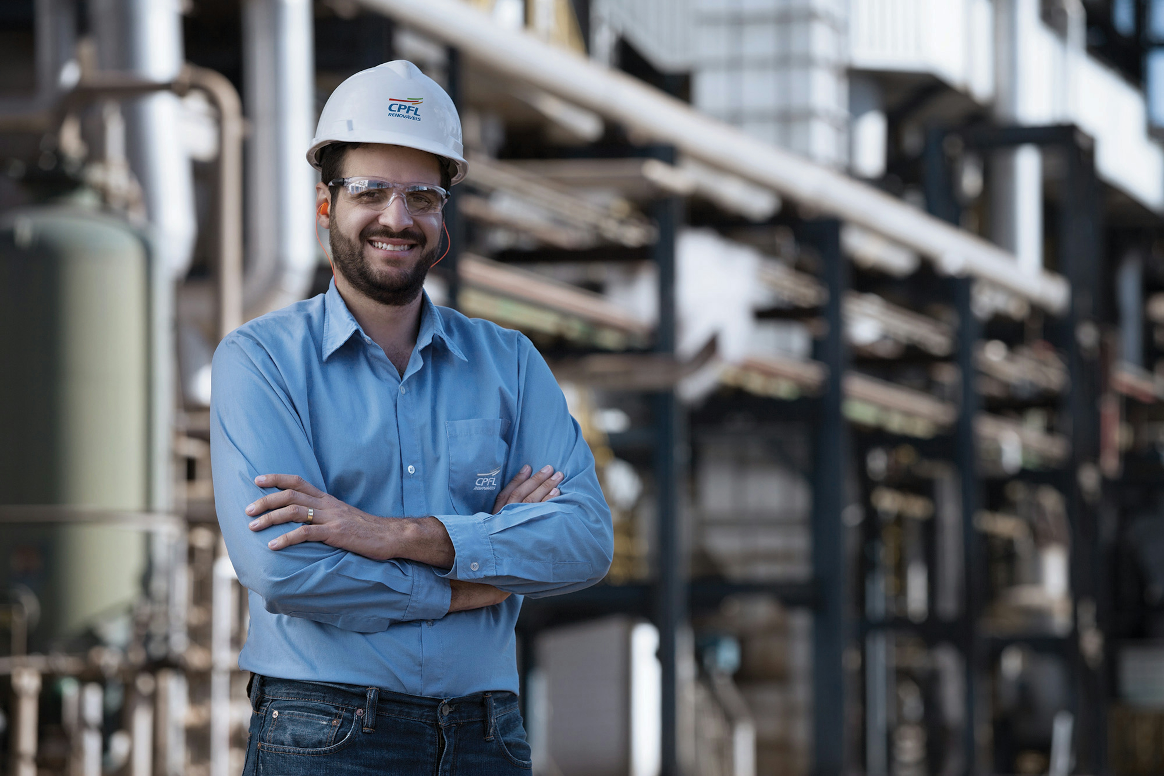 Homem de braços cruzados na frente de uma industria