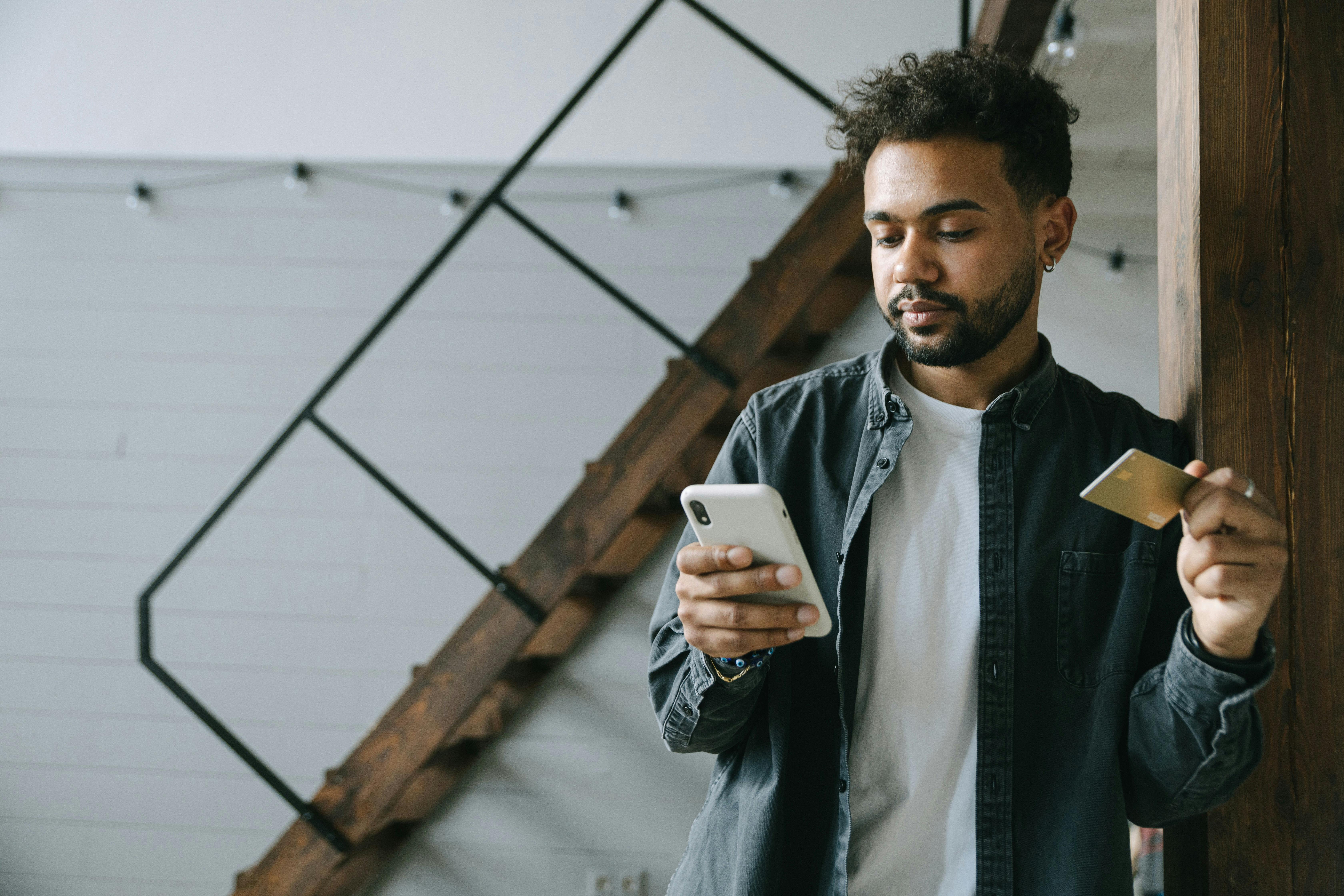 Man looking at phone using credit card