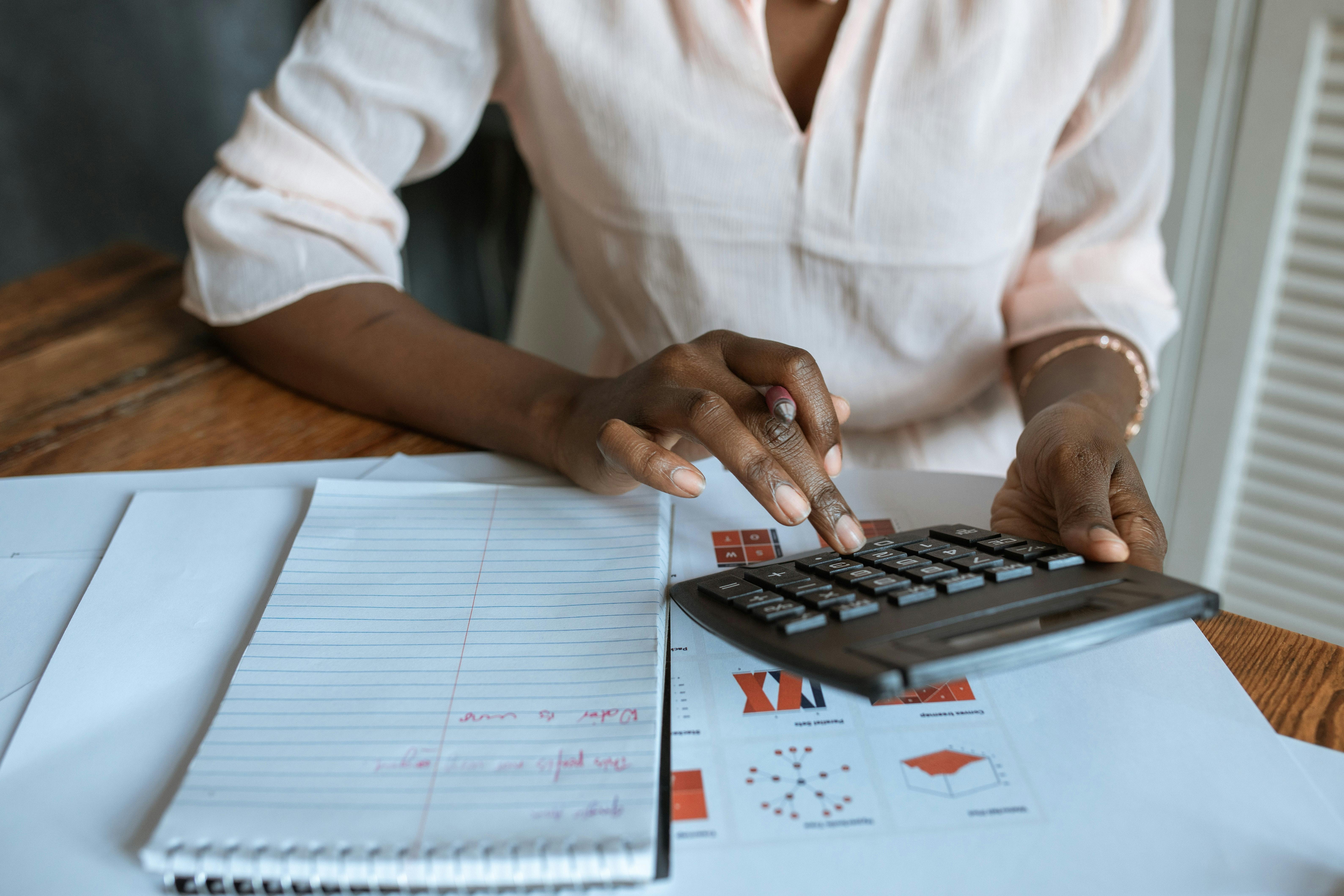 Woman at desk using calculator with notepad