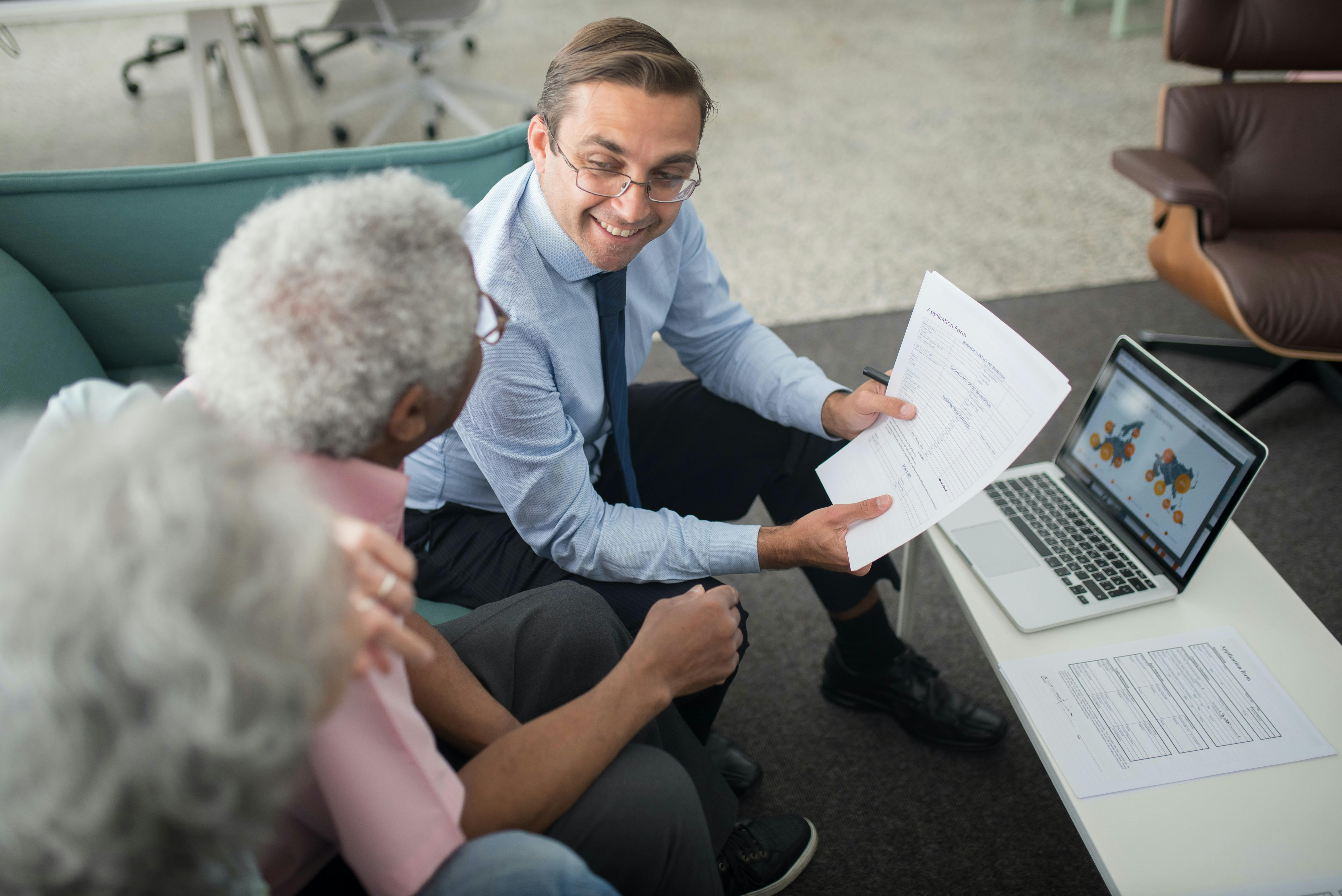 Couple seated on couch with accountant reviewing documents