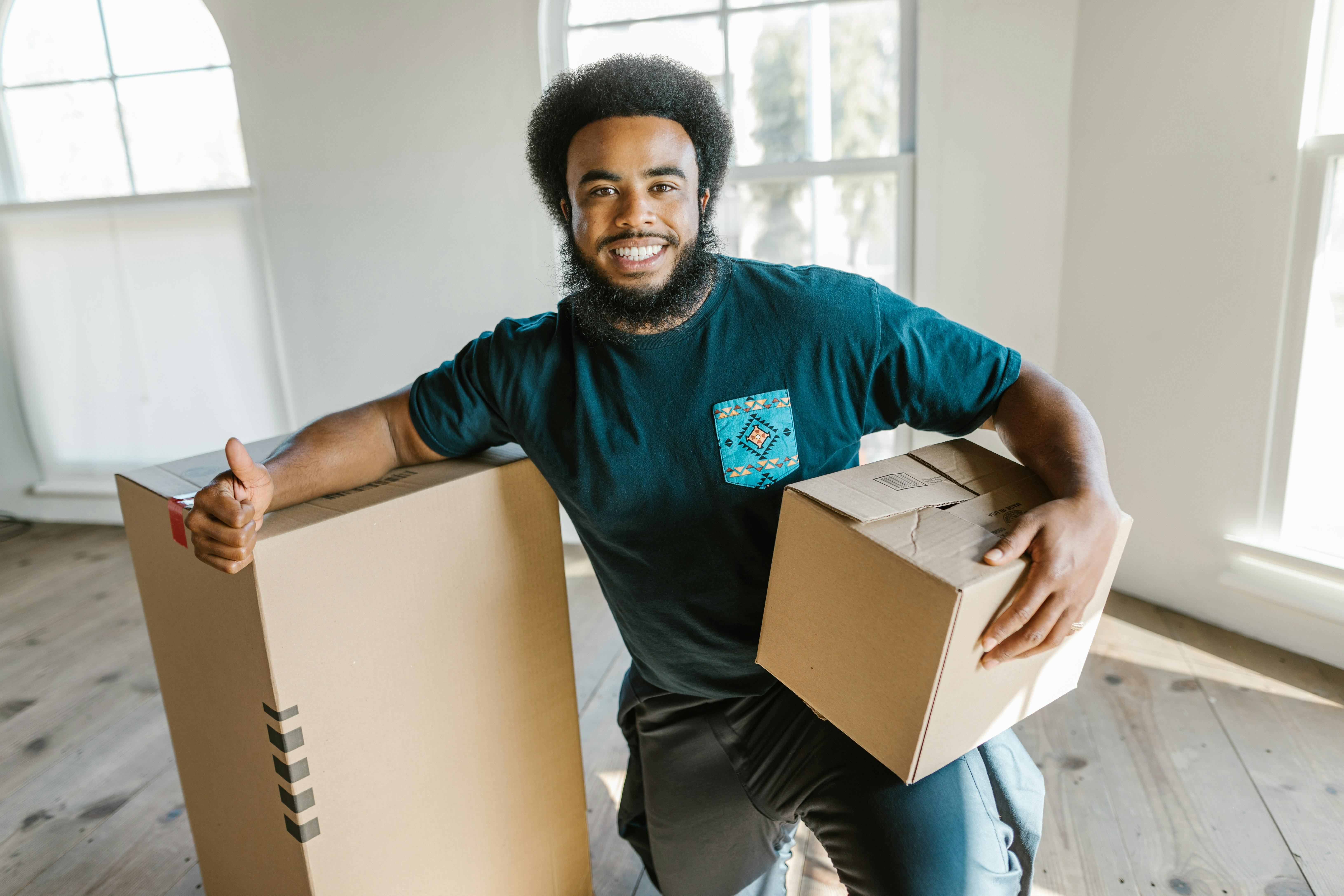 Young man with moving boxes giving thumbs up