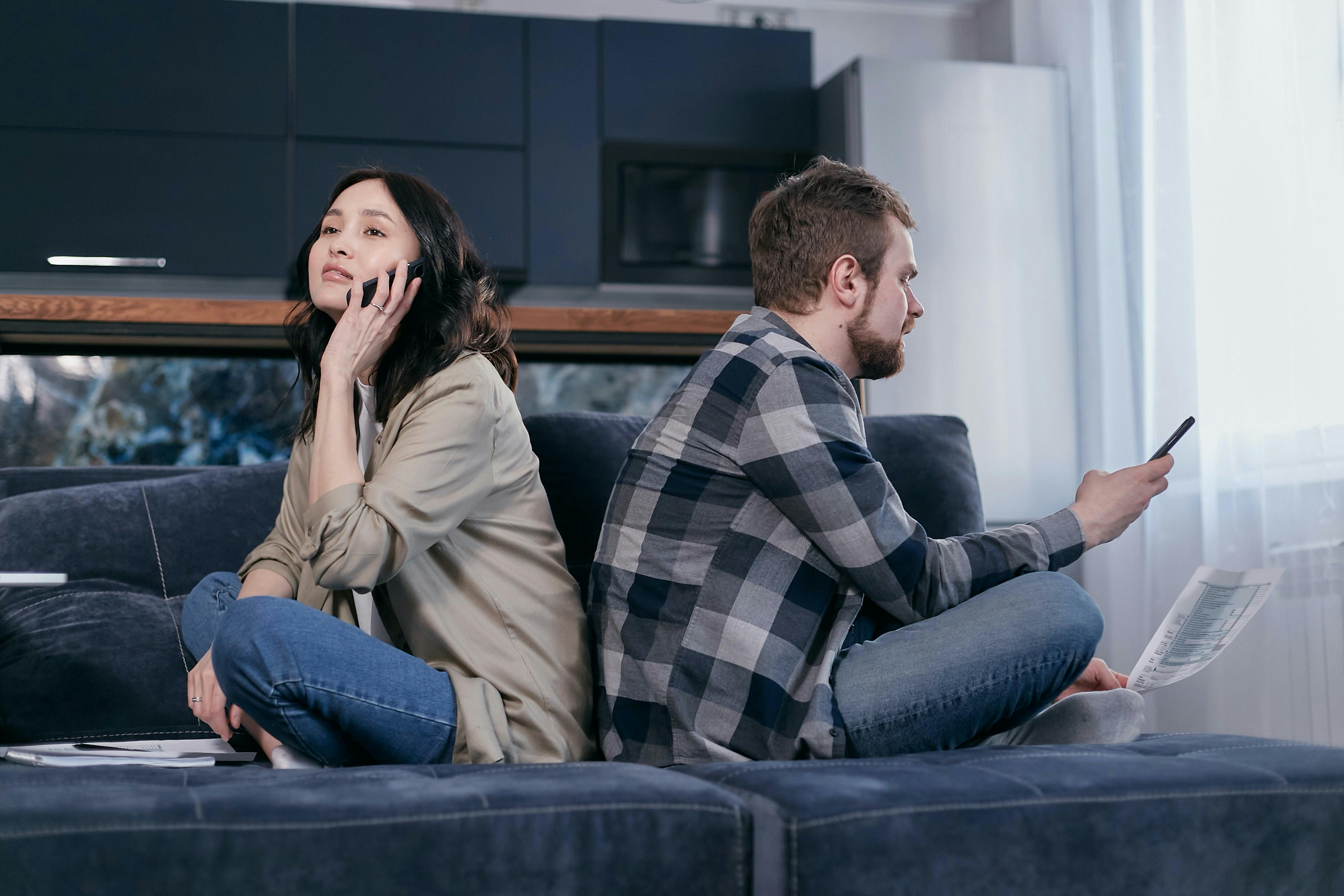 Man and woman seated on couch using mobile phones
