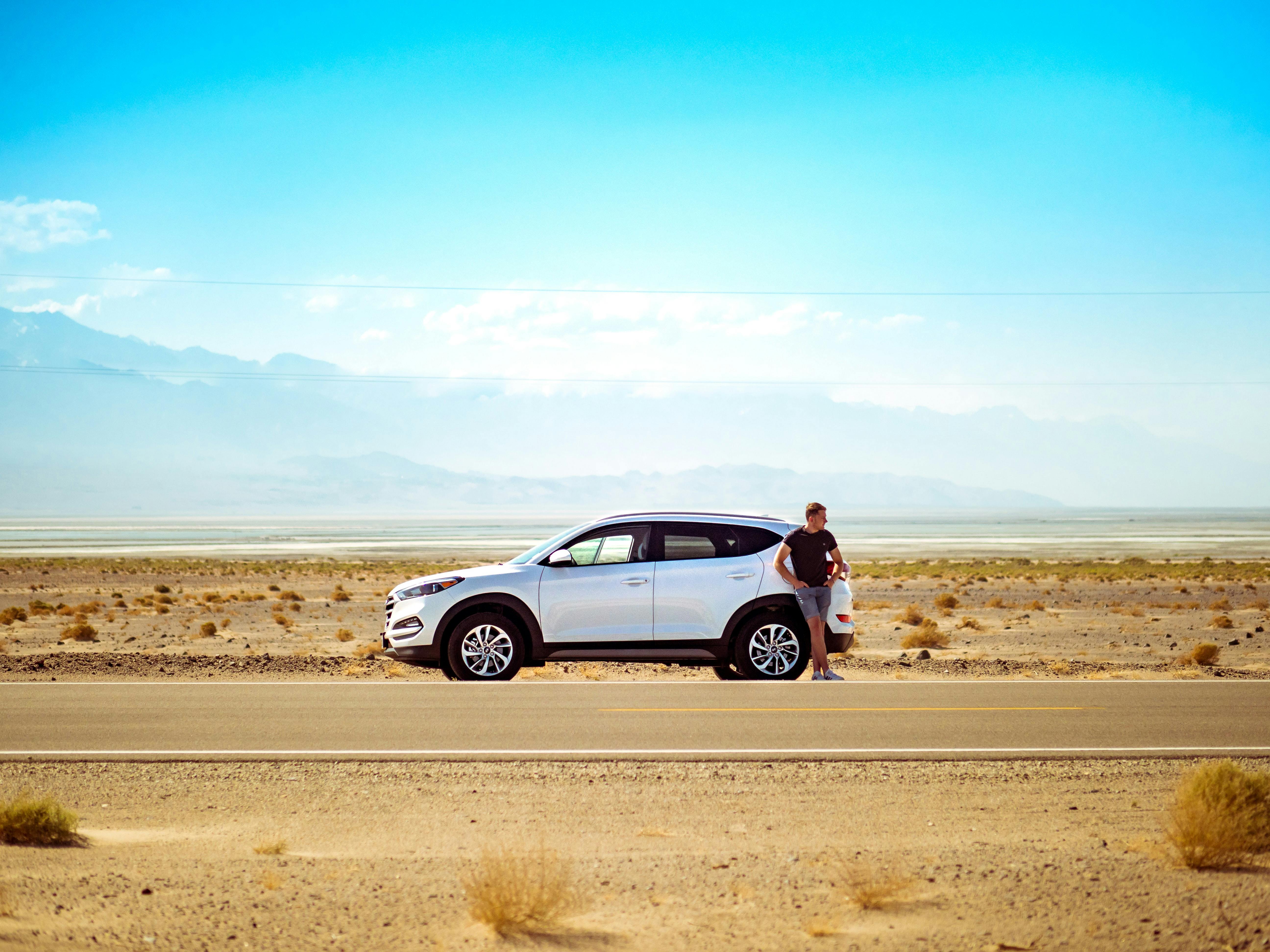 Man standing next to car in desert