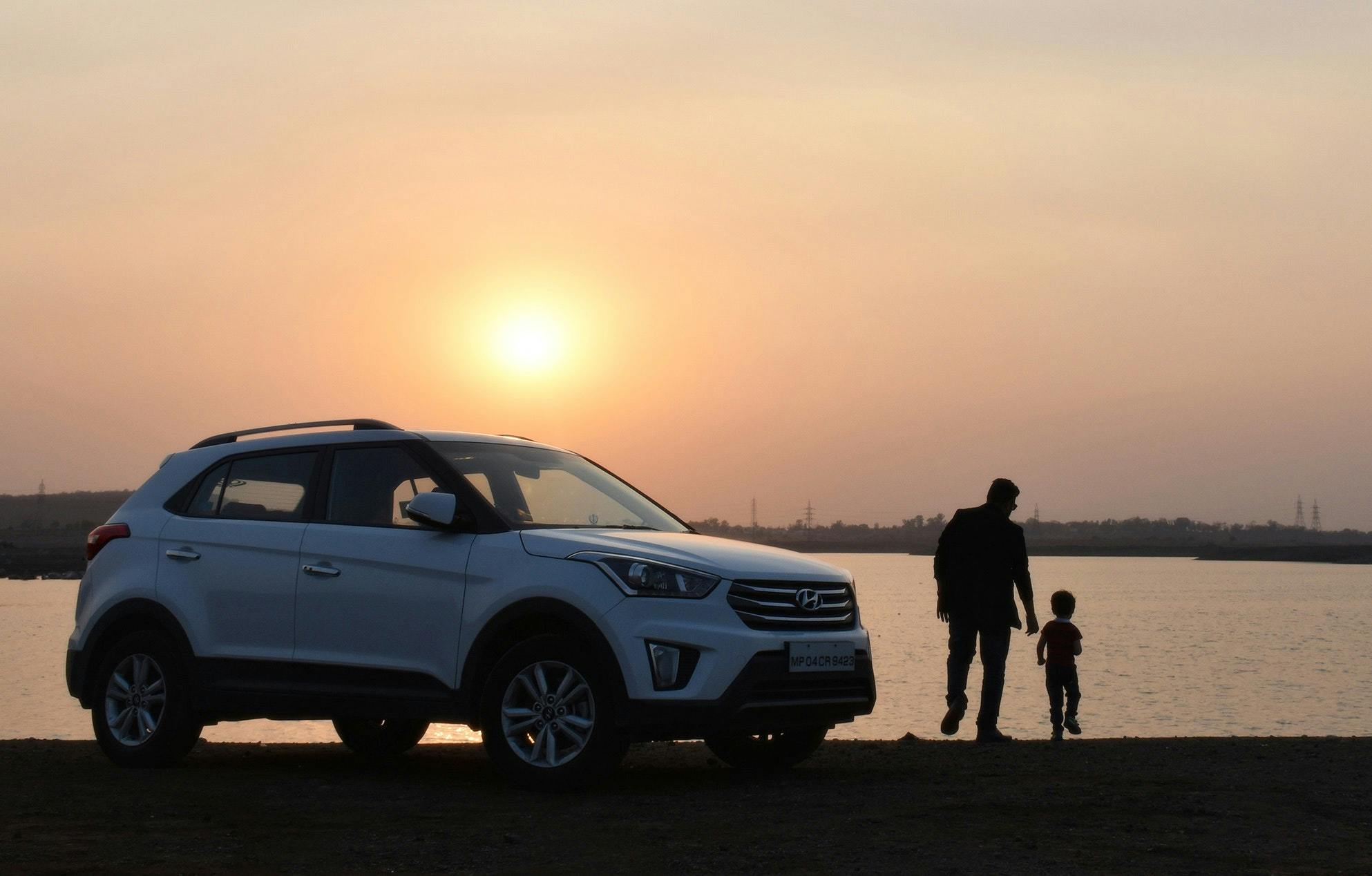 Man with son outside car in front of lake