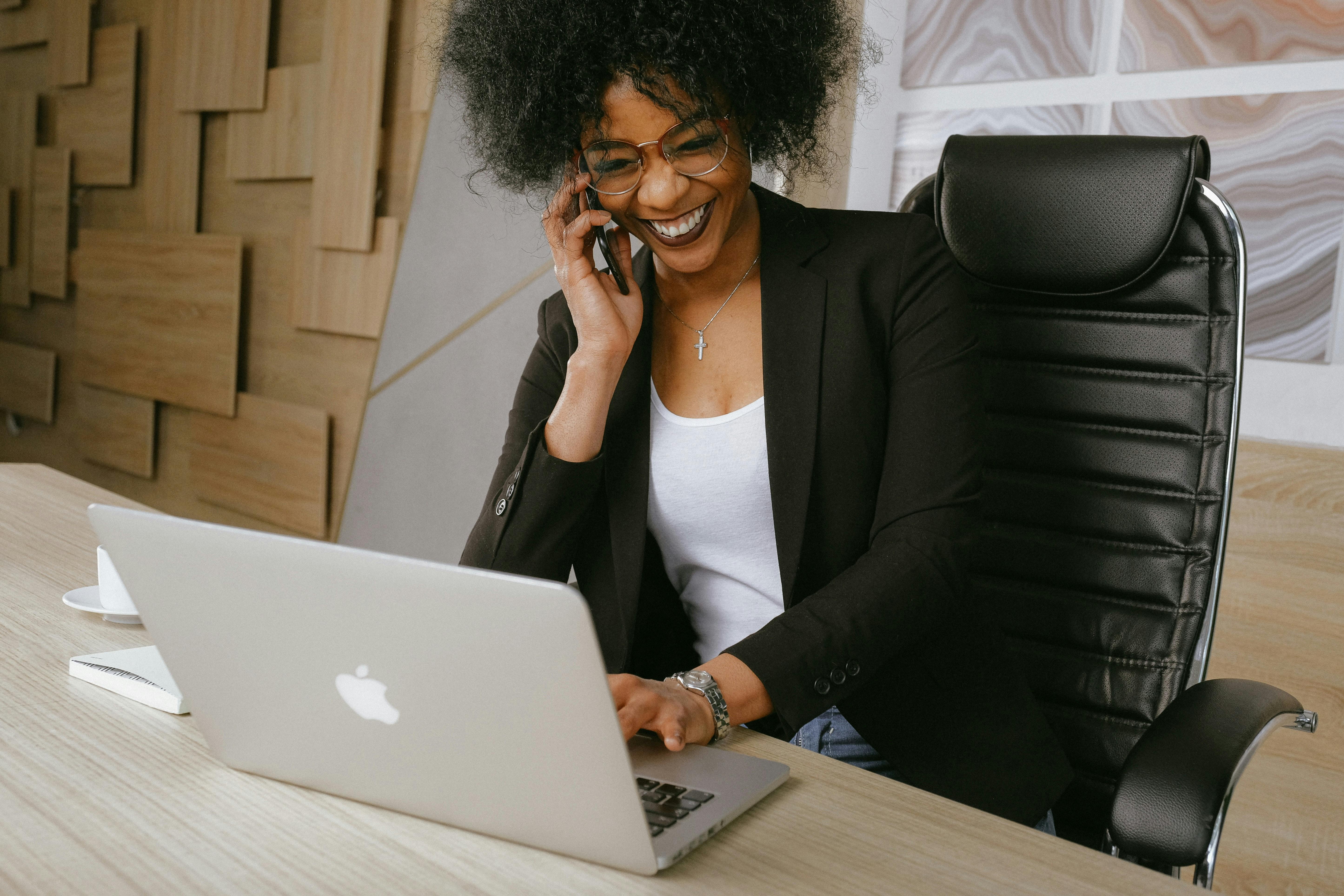 Woman entrepreneur smiling while using phone and laptop