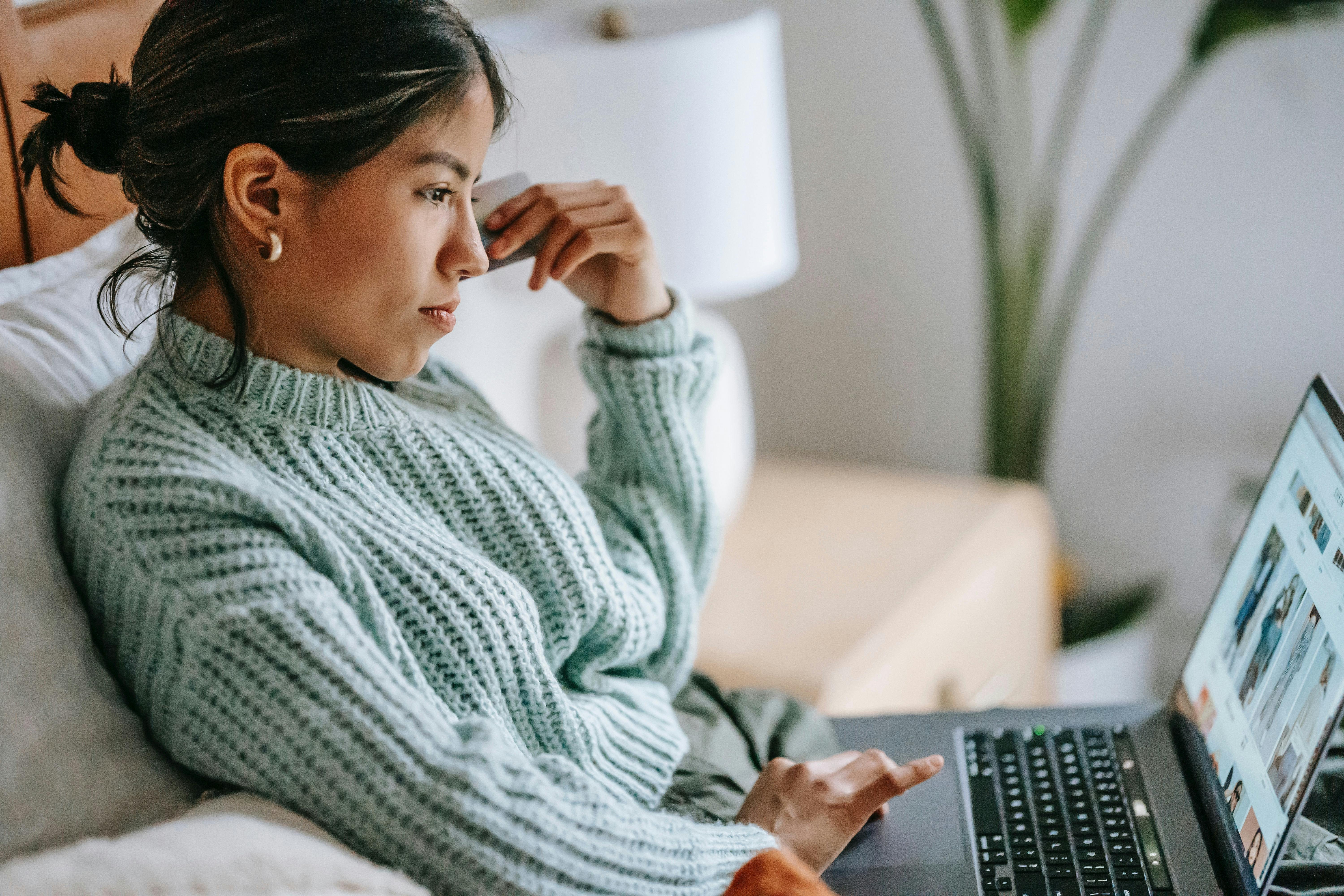 Woman on couch reading article on laptop