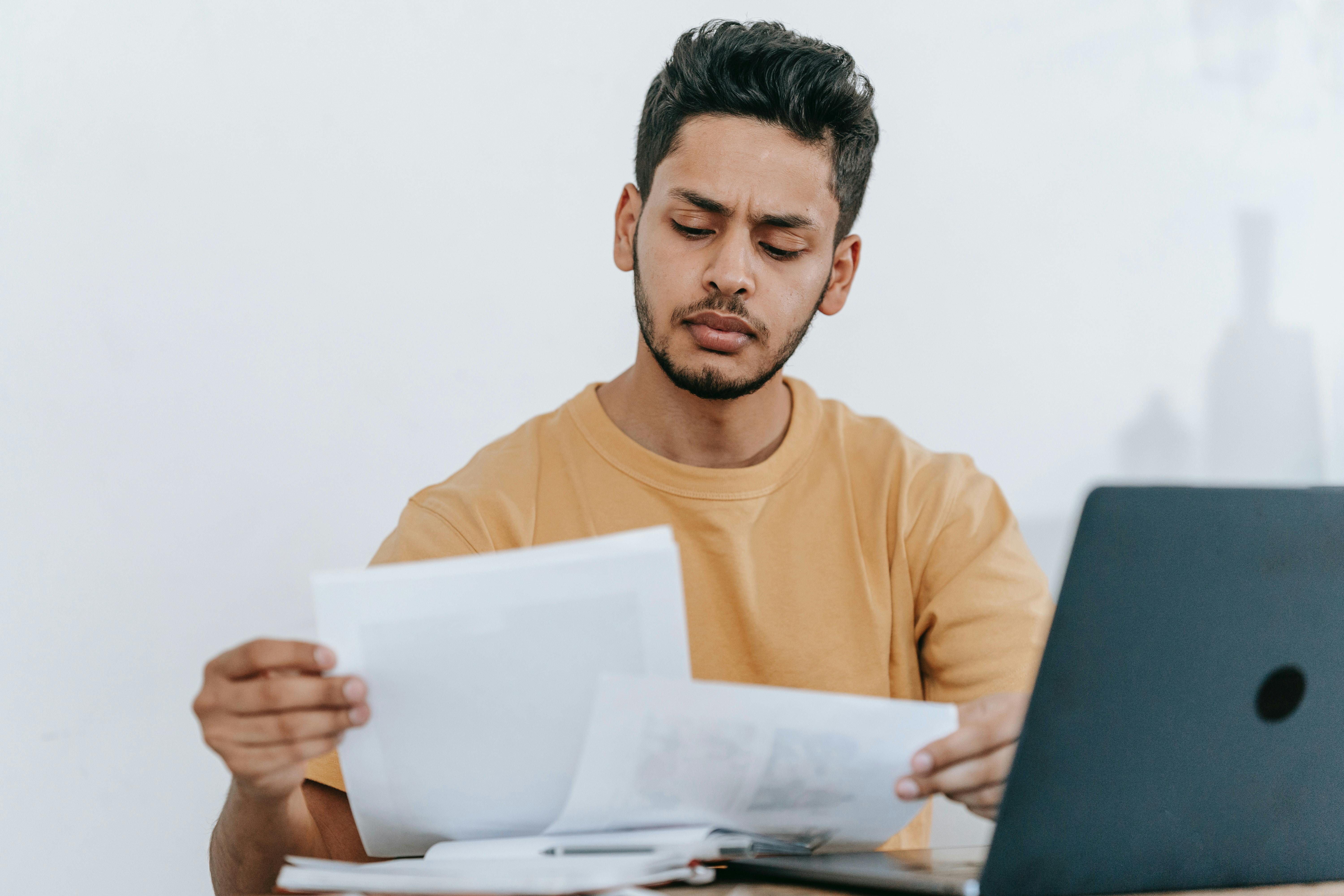 Young man with laptop reviewing documents