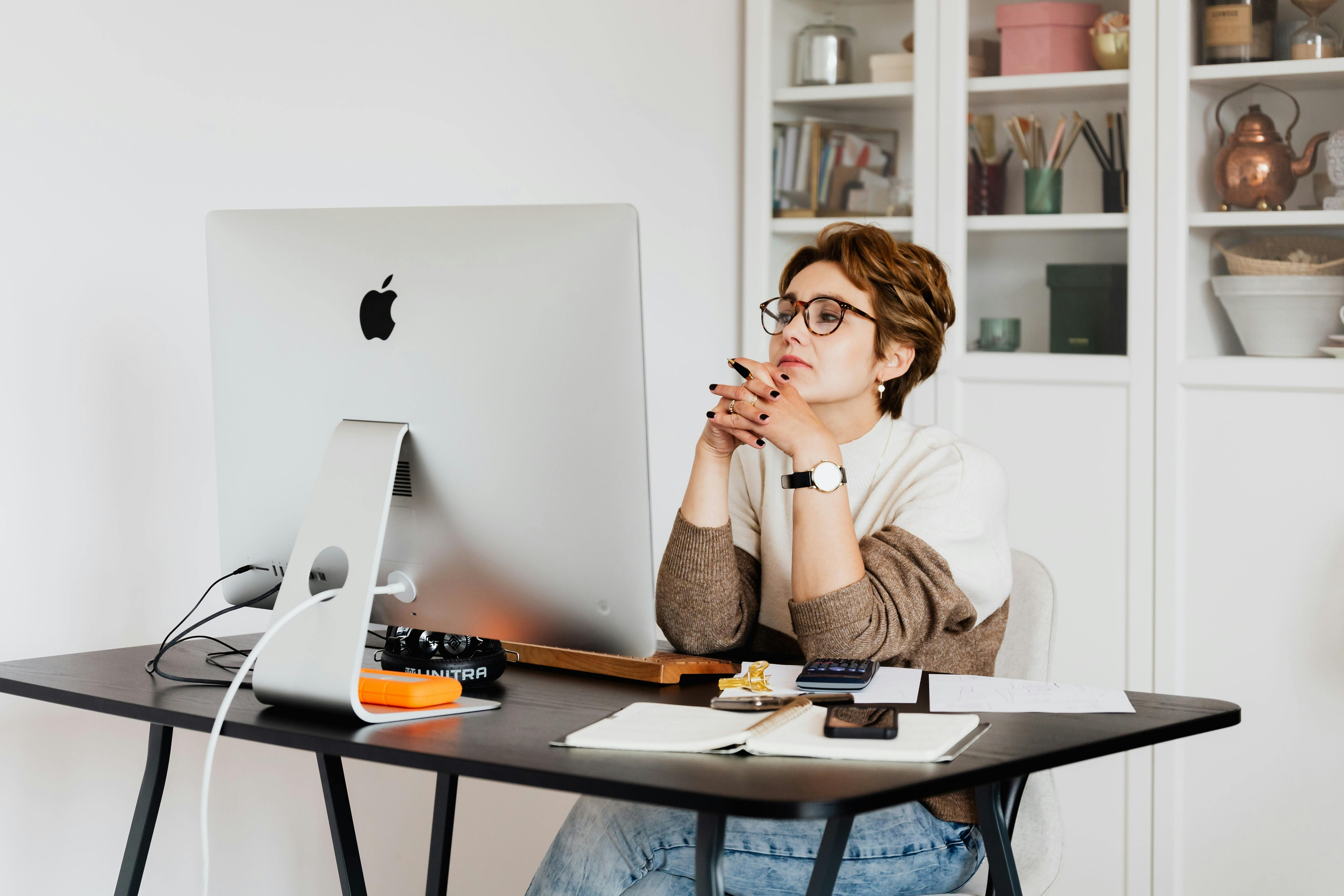 Woman thinking and looking at laptop