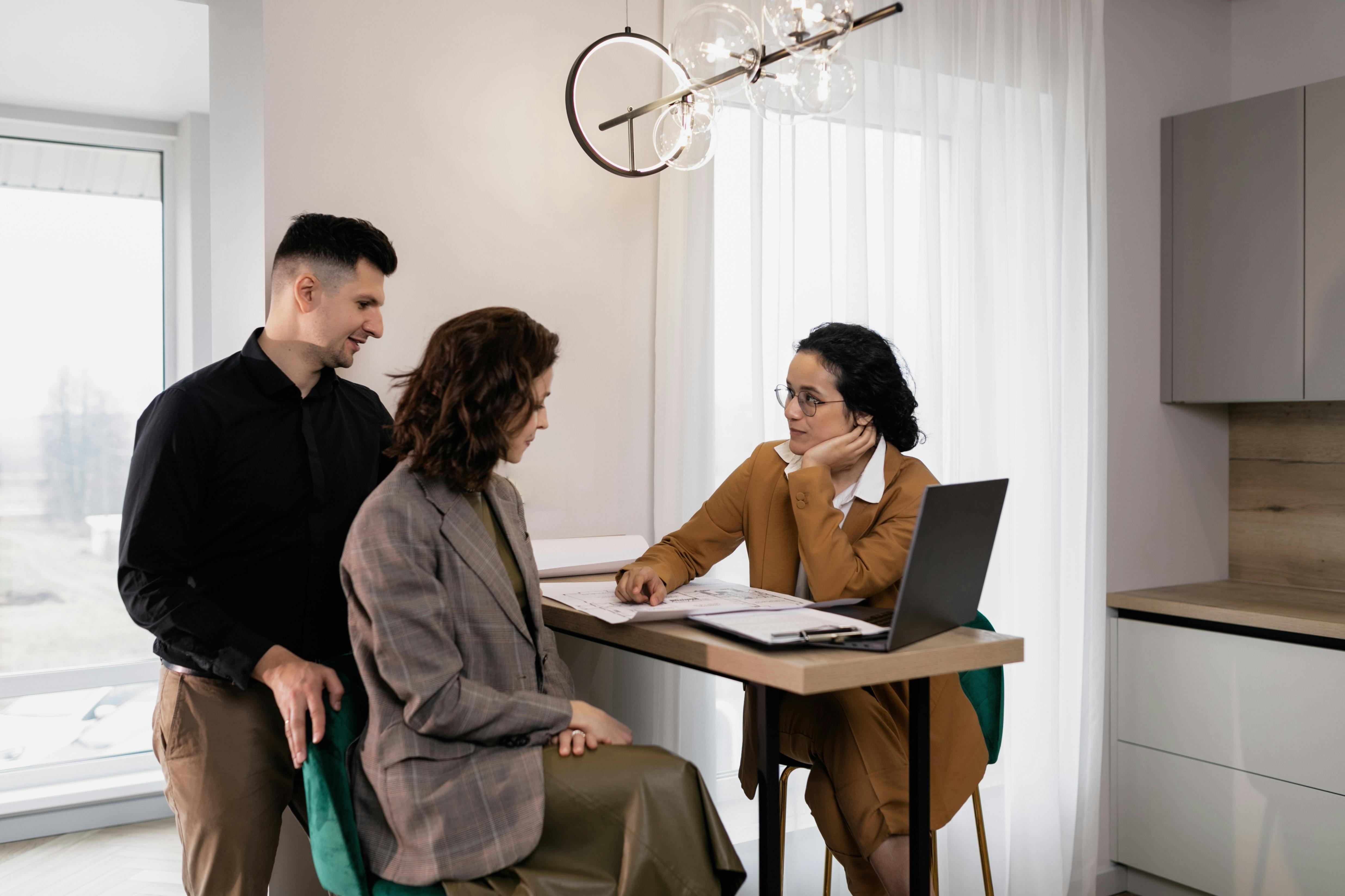 Realtor with couple sitting at counter reviewing documents