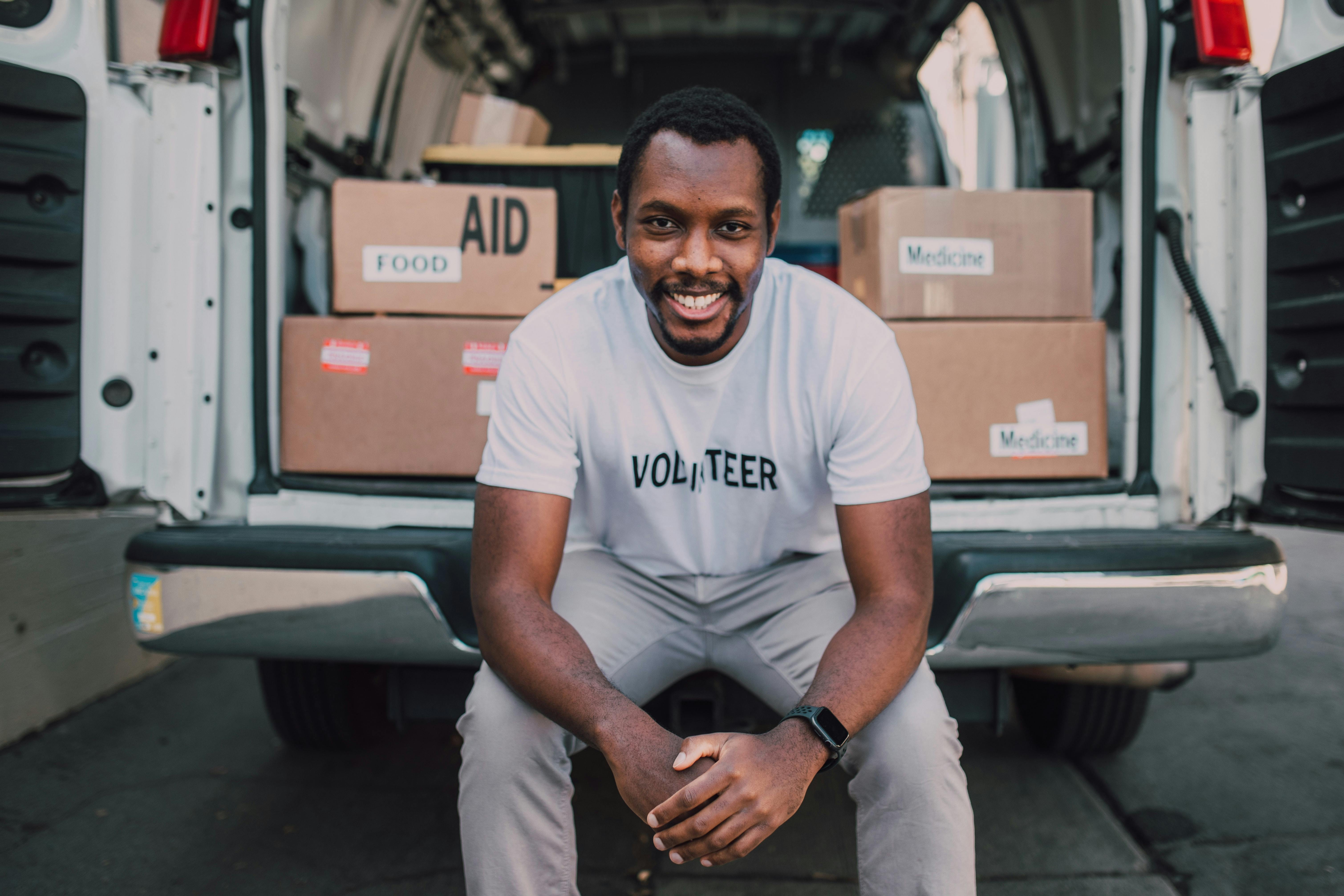 Man sitting on delivery van and smiling