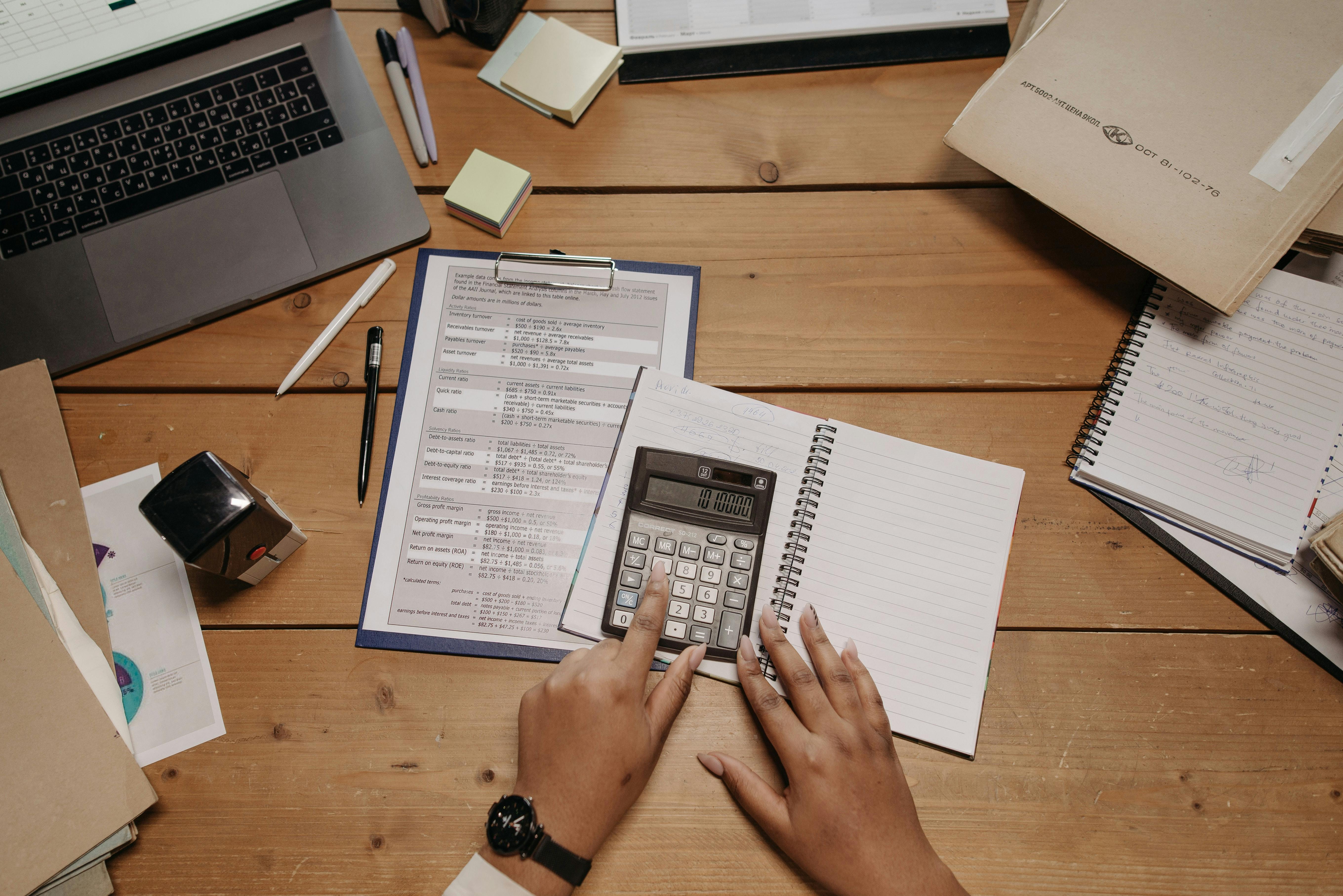 Hands using calculator and notepad