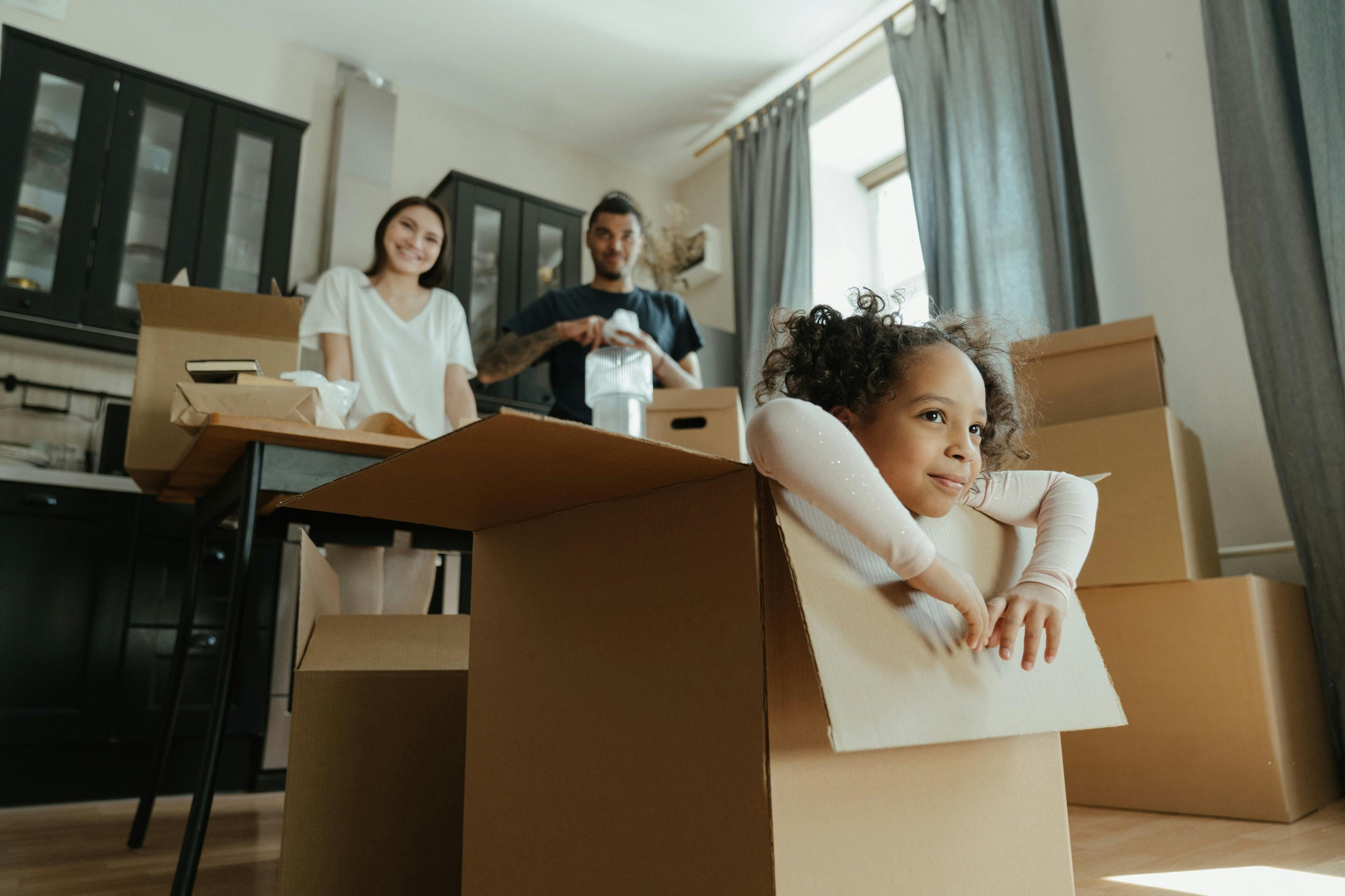 Child in moving box with parents smiling in background