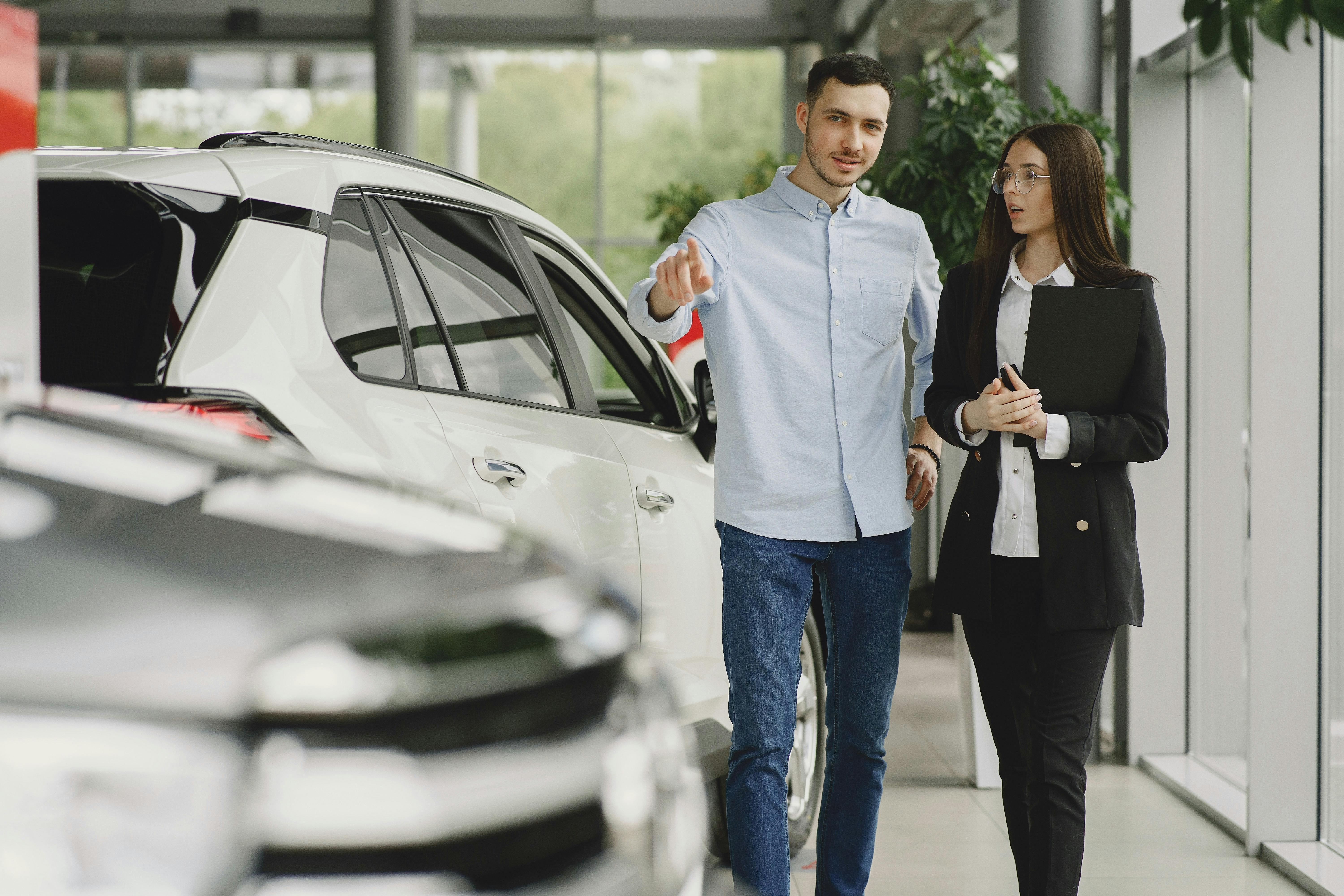 Man and car saleswoman walking at dealership