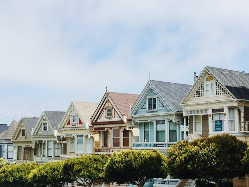 Multicolored row homes on street with trees