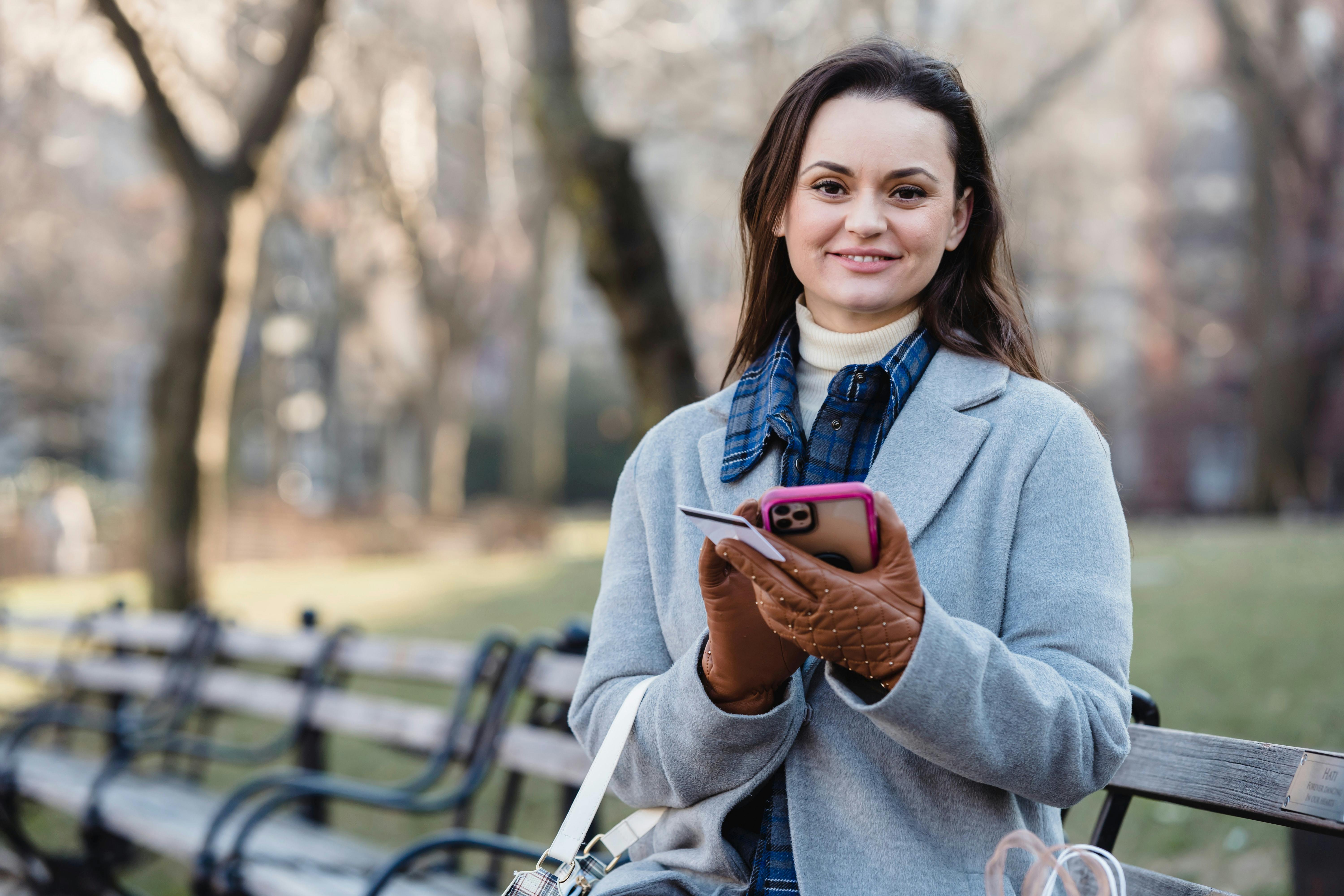 Woman in park with phone and credit card in hand