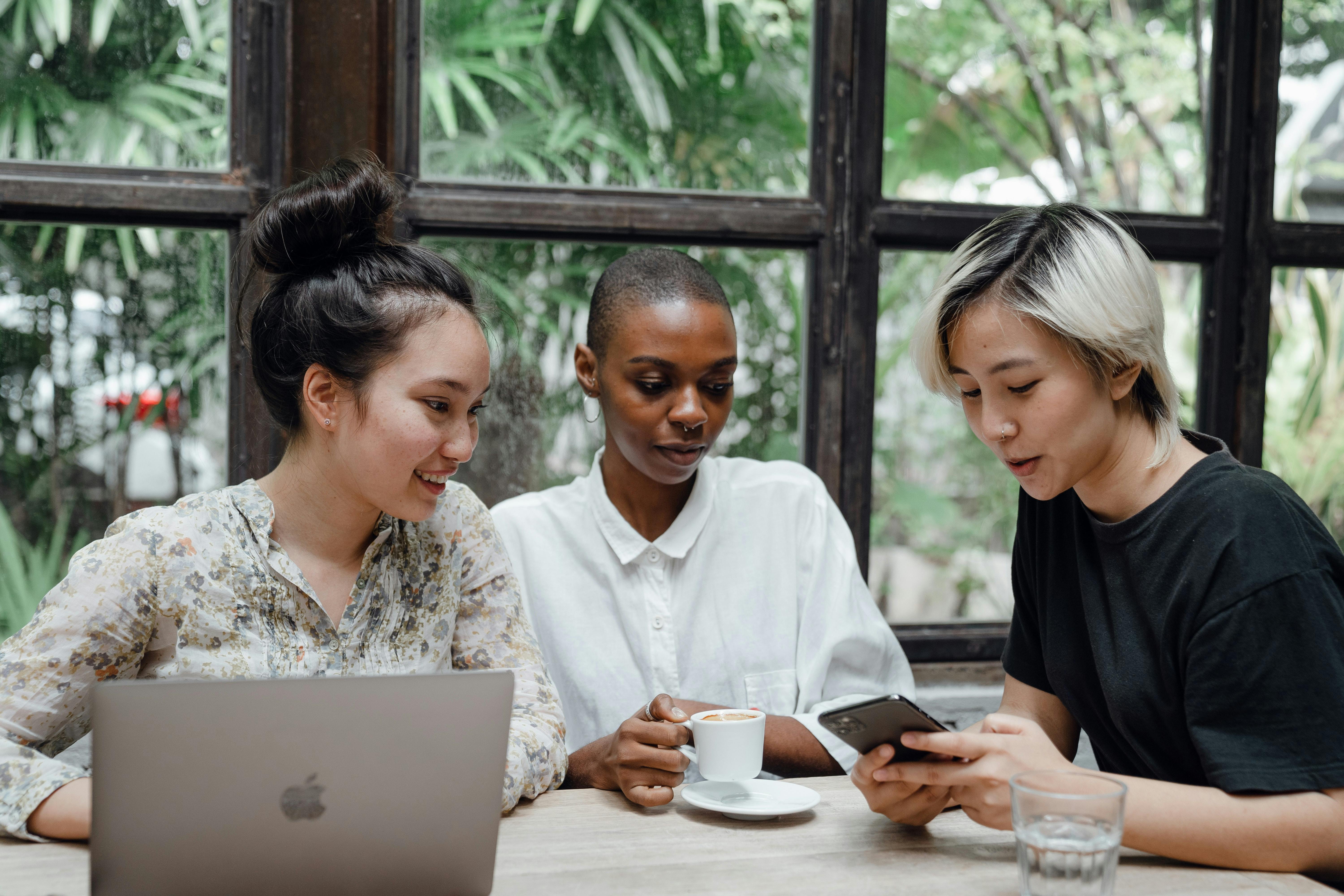 Three women at desk looking at smartphone