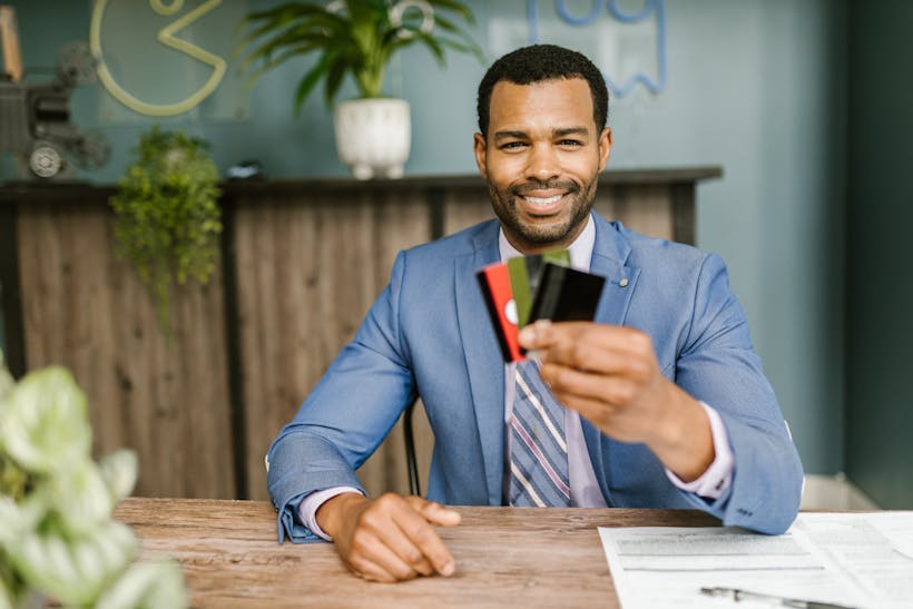 Man in suit smiling and holding credit cards