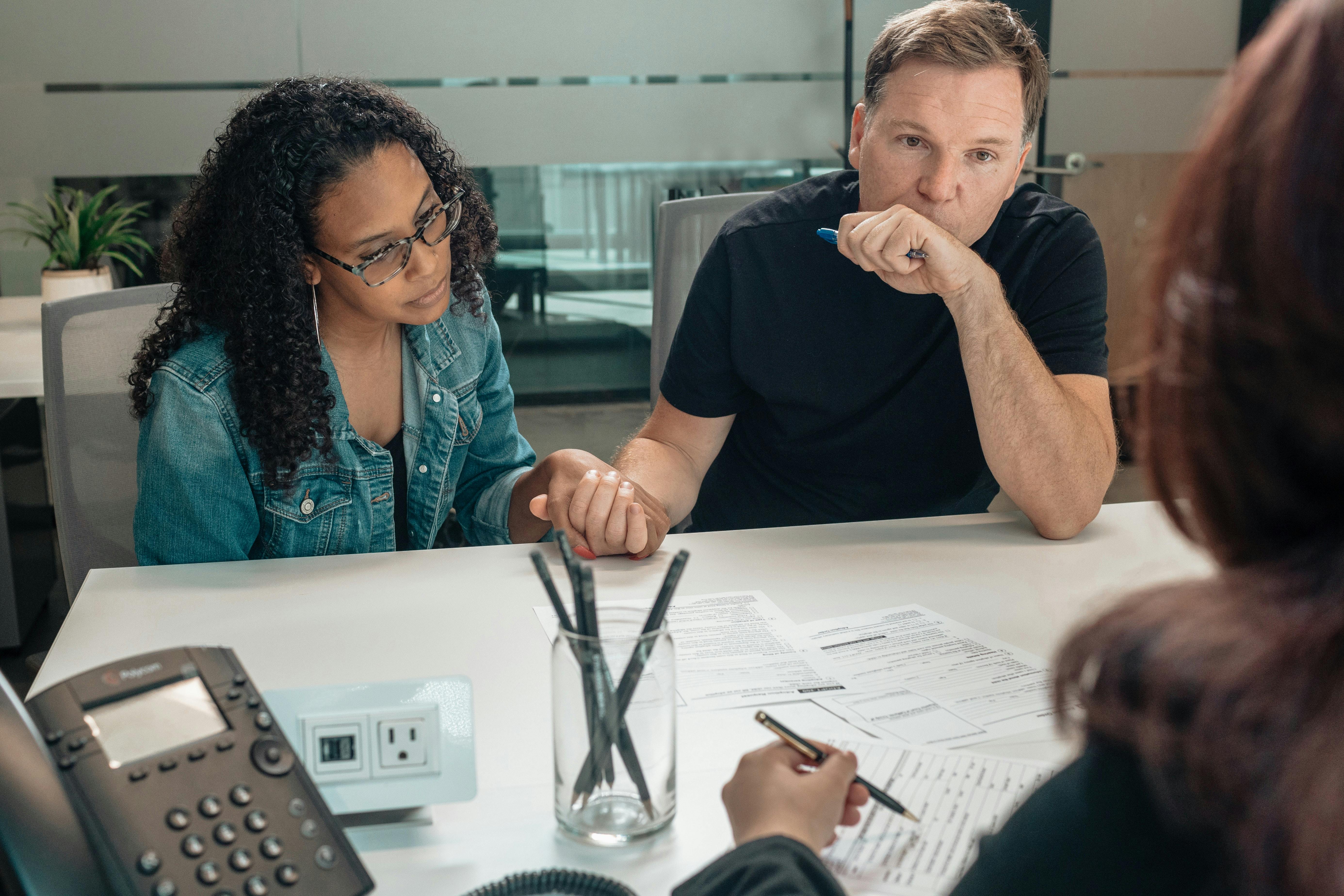 Couple speaking with financial advisor at desk