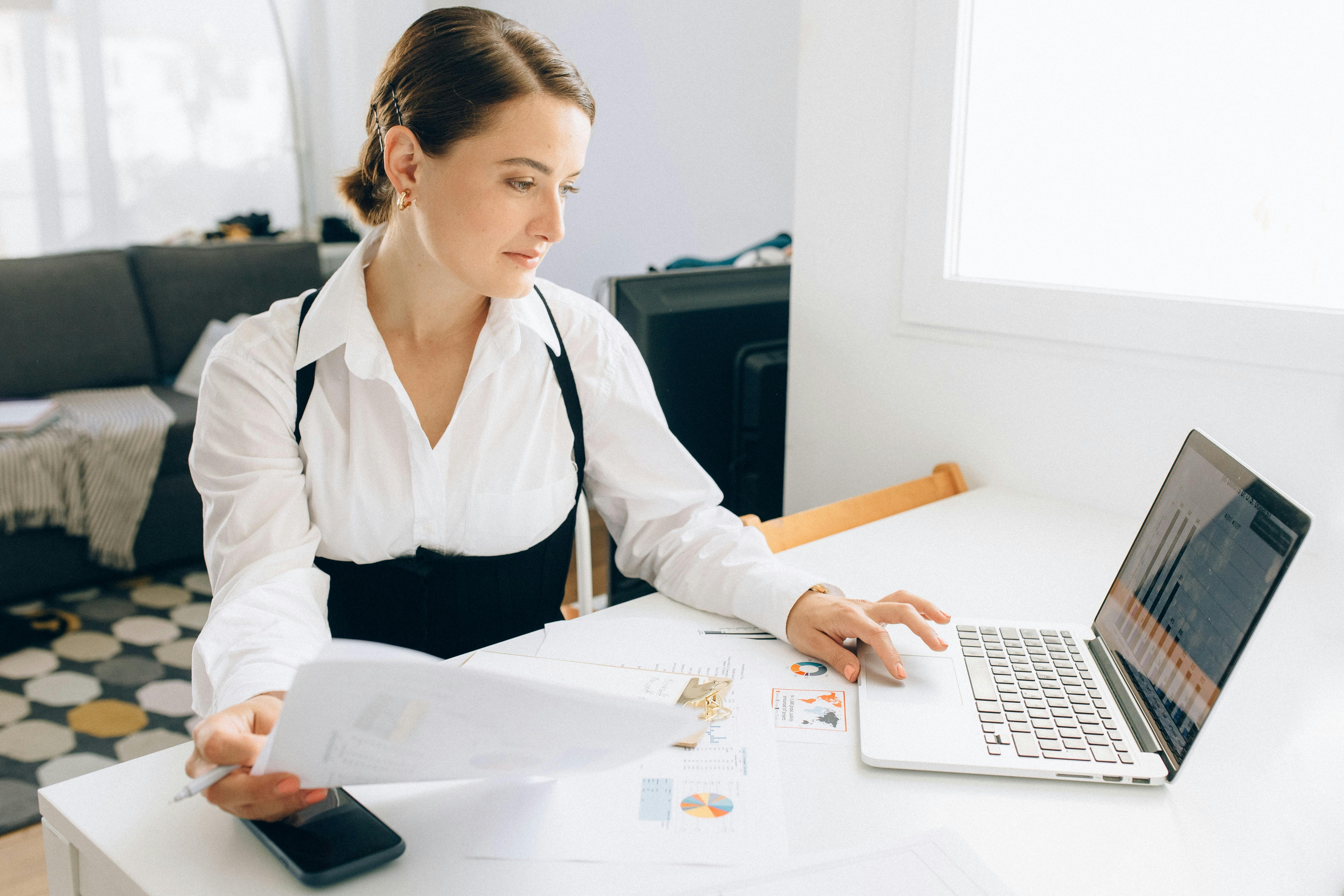 Woman at desk with laptop reviewing charts