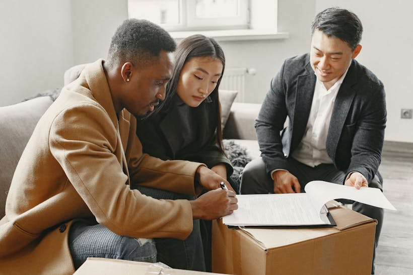 Couple with realtor signing documents with moving boxes