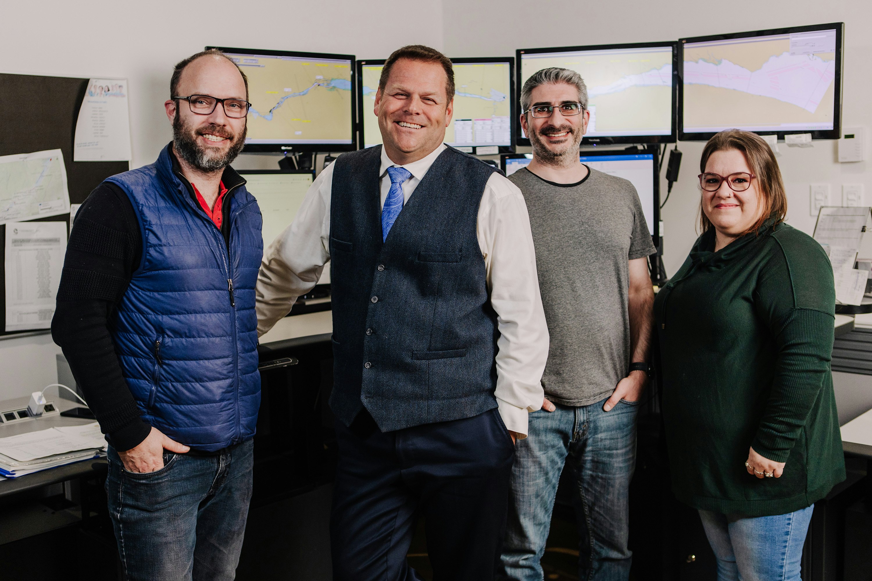 Quatre répartiteurs, soit trois hommes et une femme, posent tout sourire devant un poste de travail.