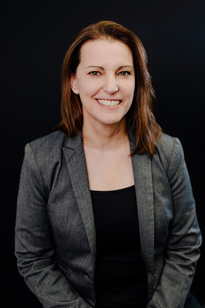 Portrait professionnel d’une femme posée devant un fond noir.