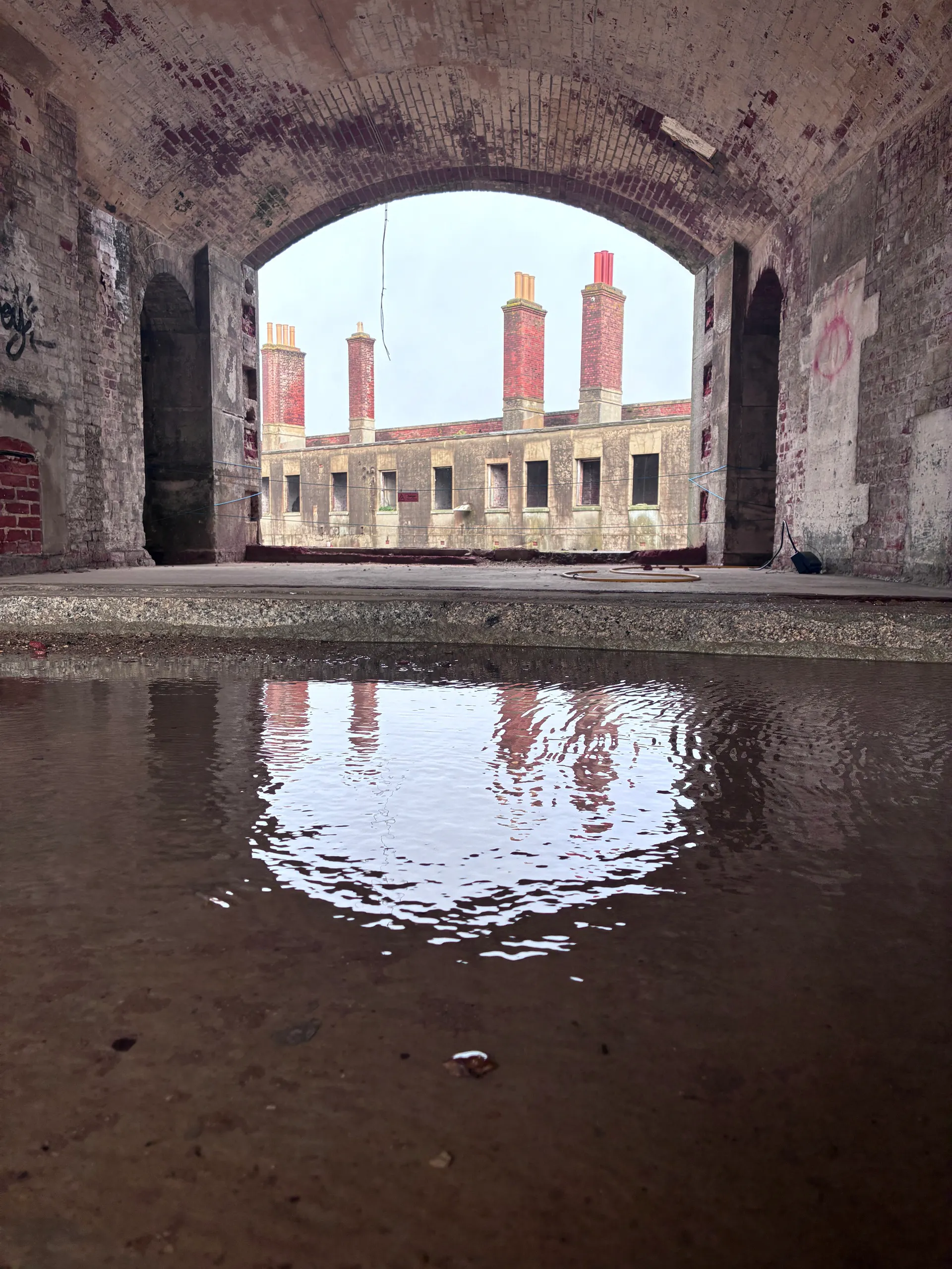 The barrack block reflected in standing water inside a casemate