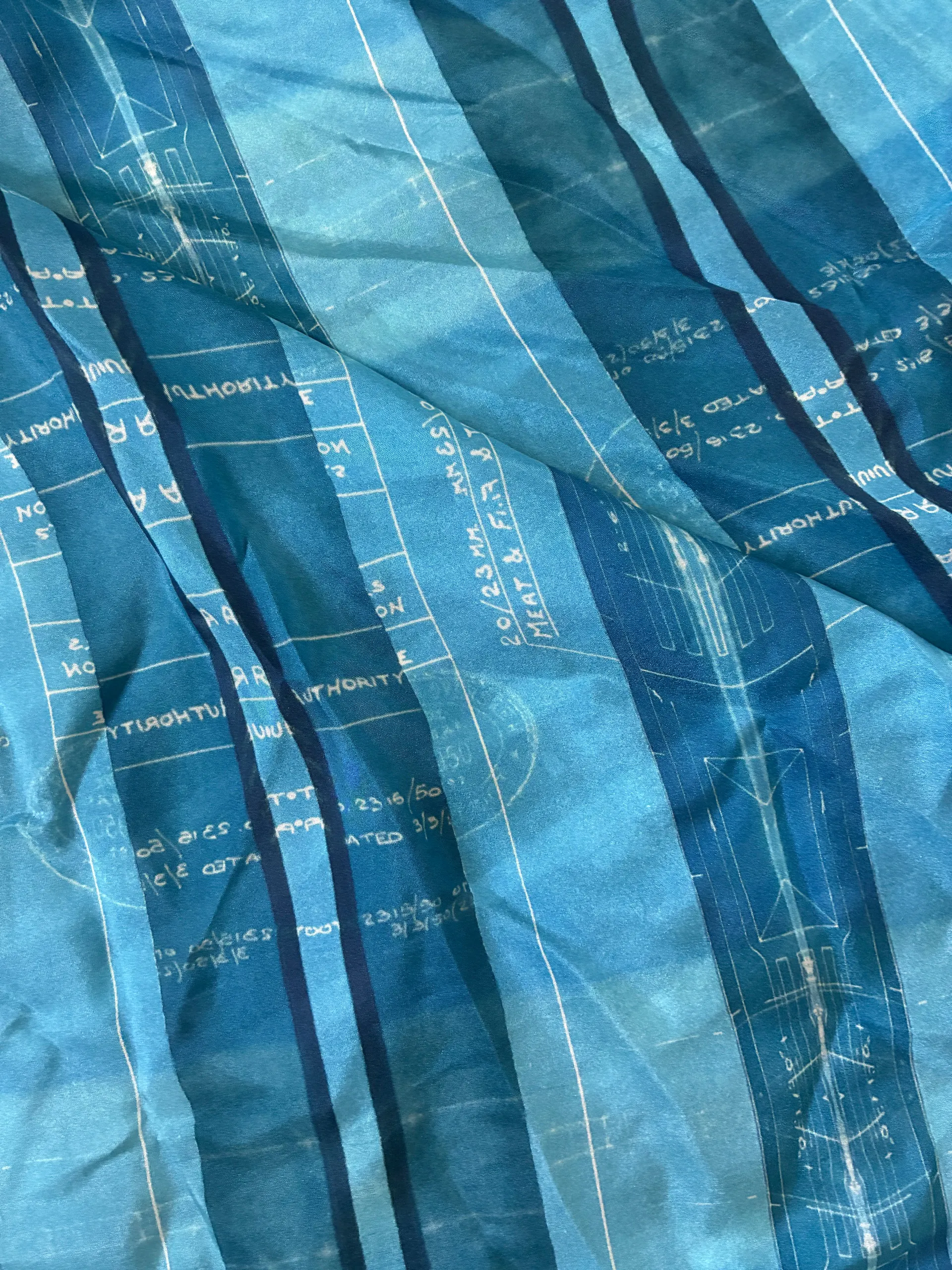 Blue printed organza in soft folds, blueprint linework following the drape