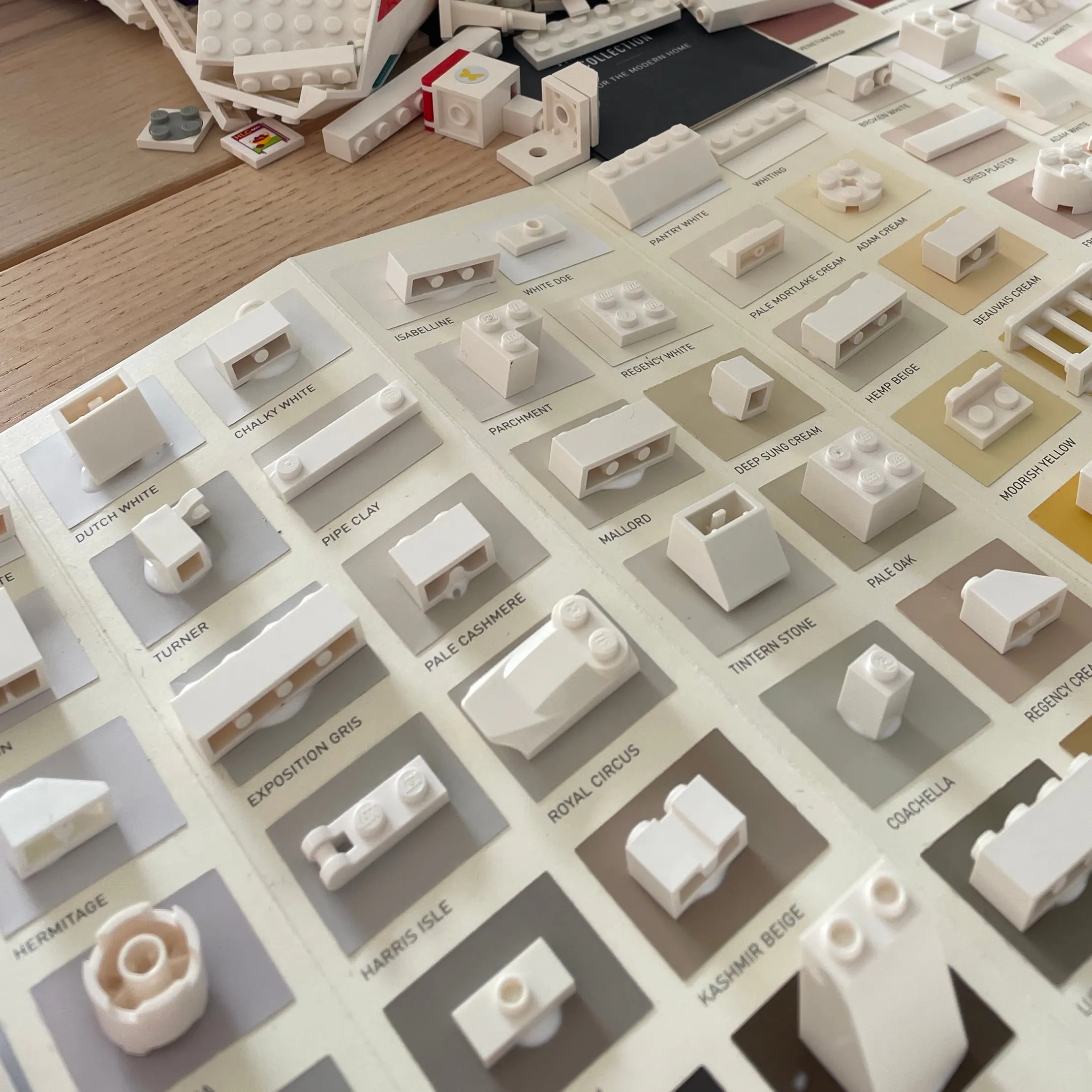 Paint charts laid on a table with loose white LEGO pieces waiting to be placed
