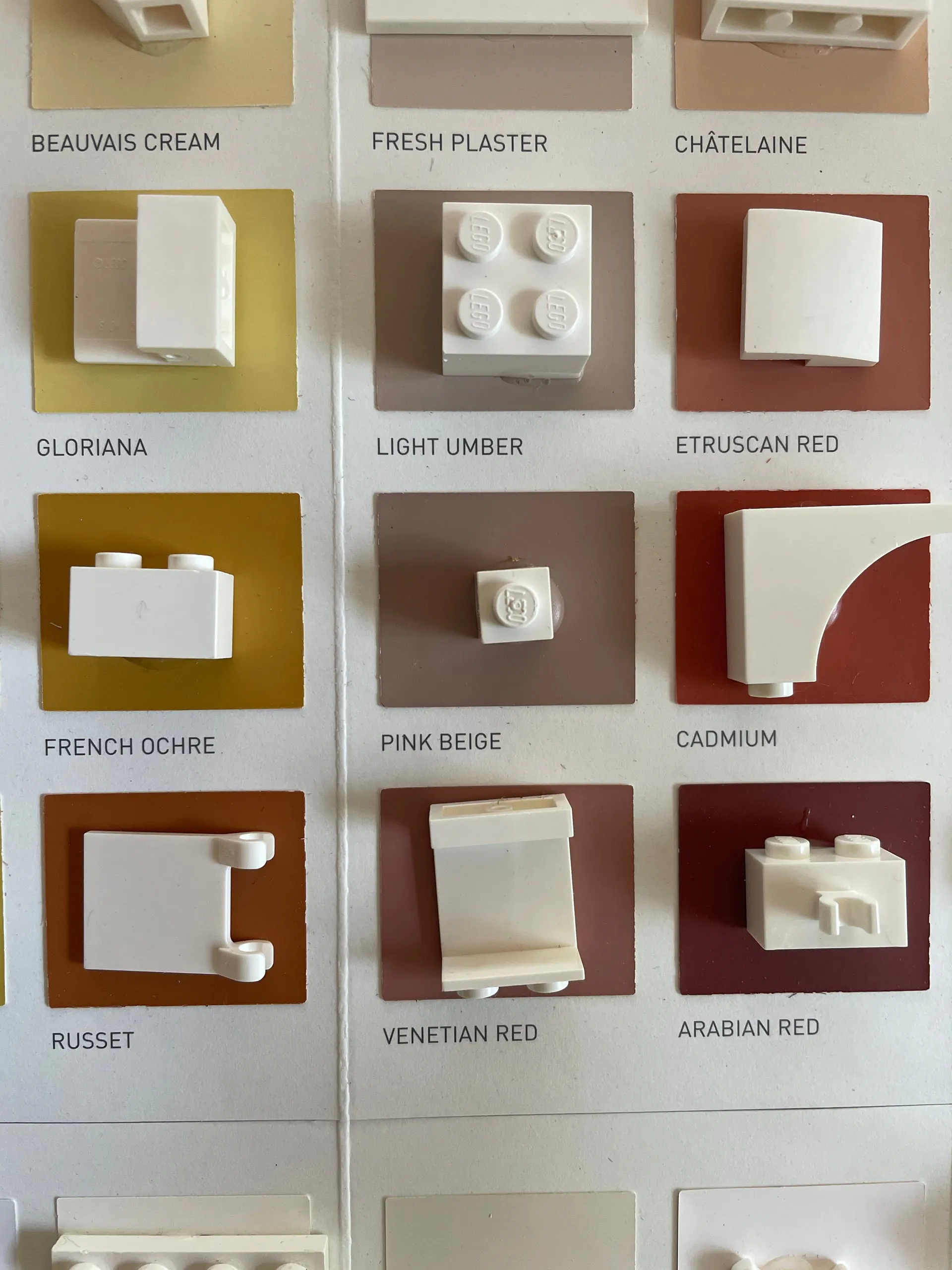 White LEGO pieces set on ochre and red paint segments, each swatch named beneath