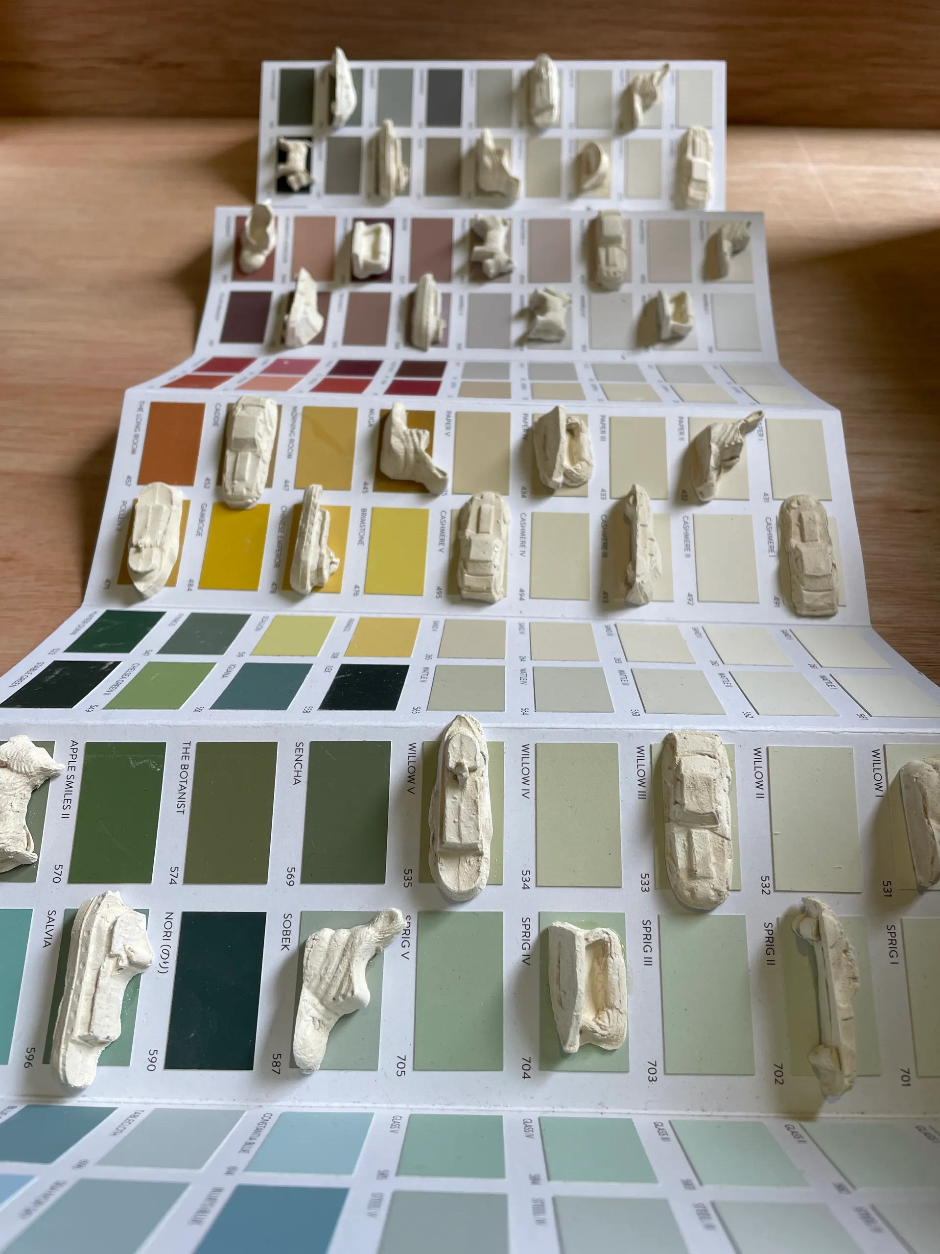 Paint colour cards fanned out, each set with a cast Monopoly token