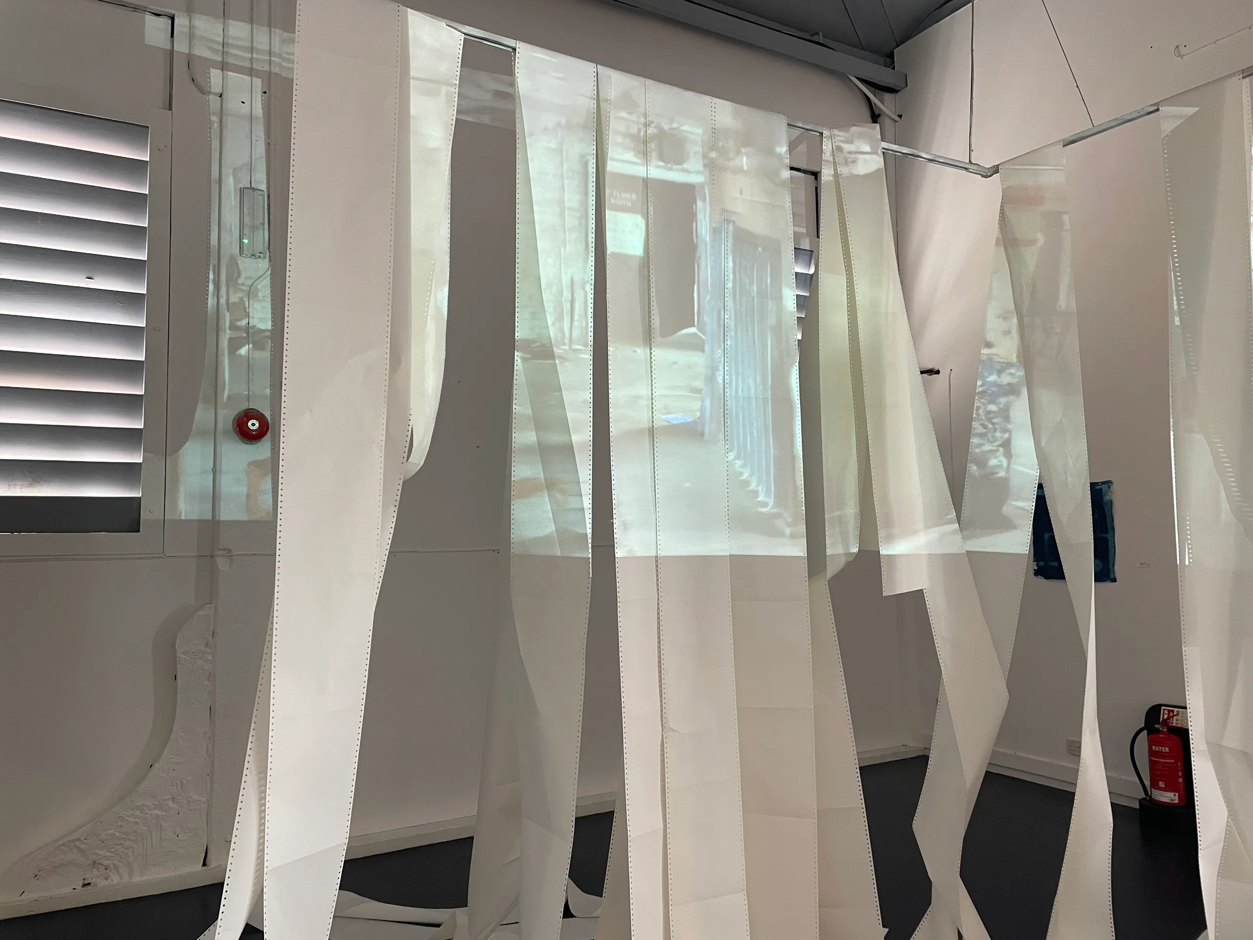 Hanging translucent strips lit by a projection in the gallery