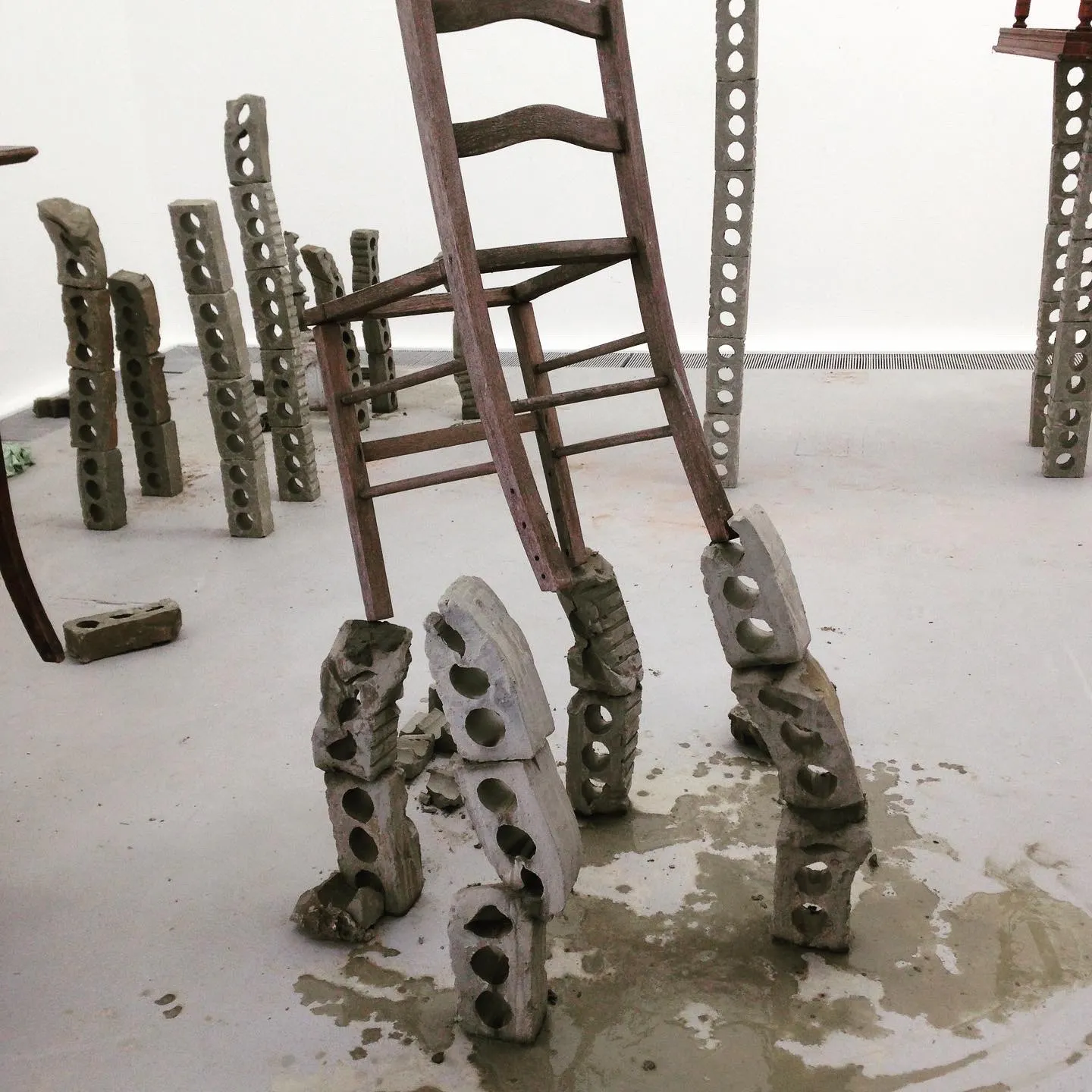 A chair standing on legs of grey brick above wet clay