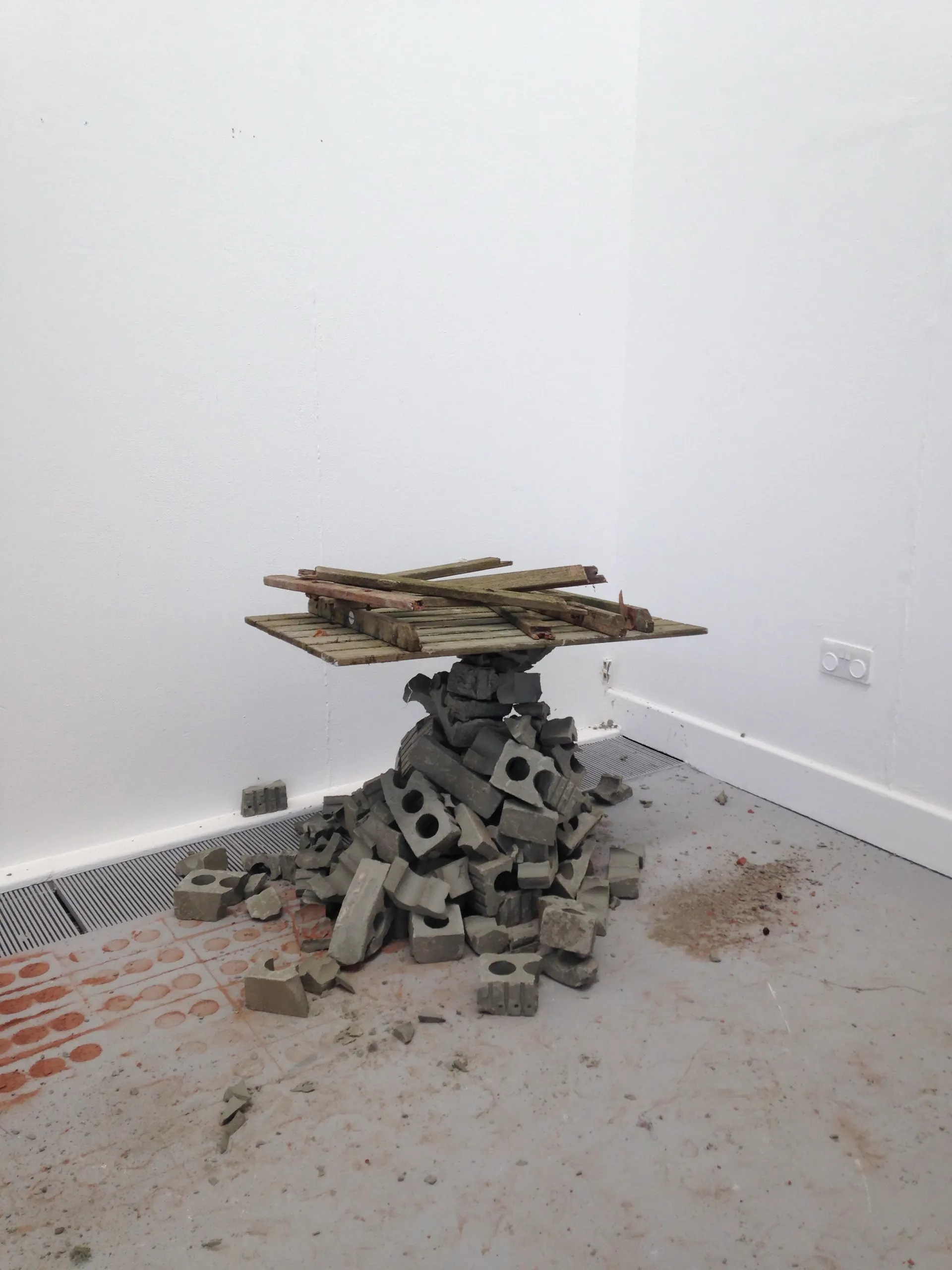 Salvaged timber resting on a pile of grey brick in a corner