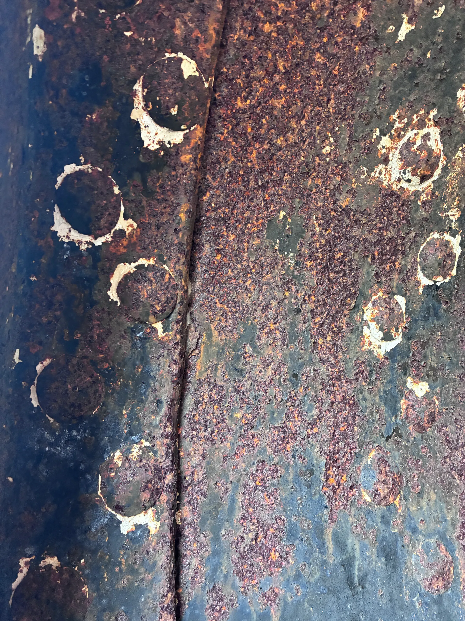 Bolt heads and blistered paint on corroded iron