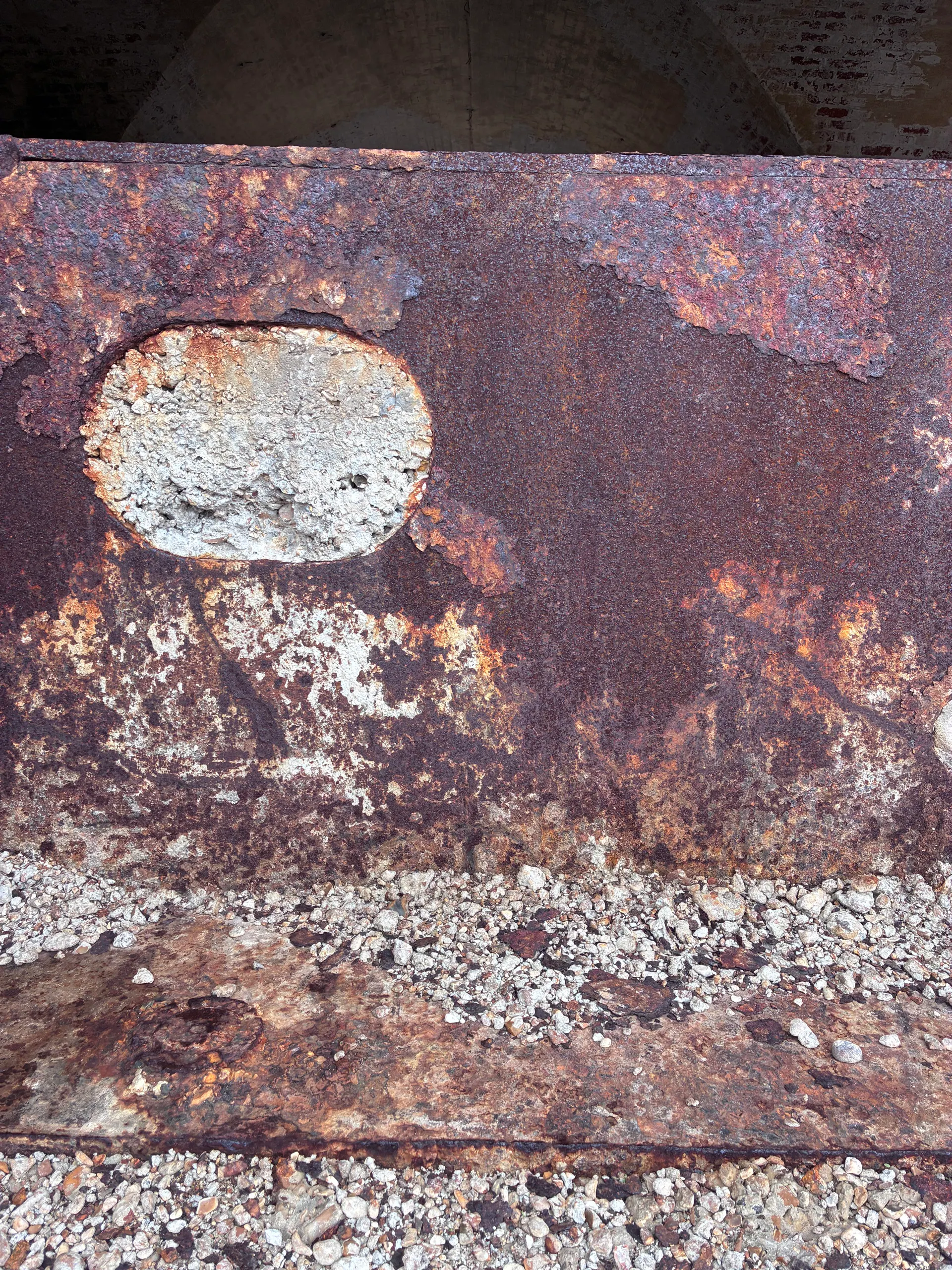 An oval concrete patch set into a rusted iron plate