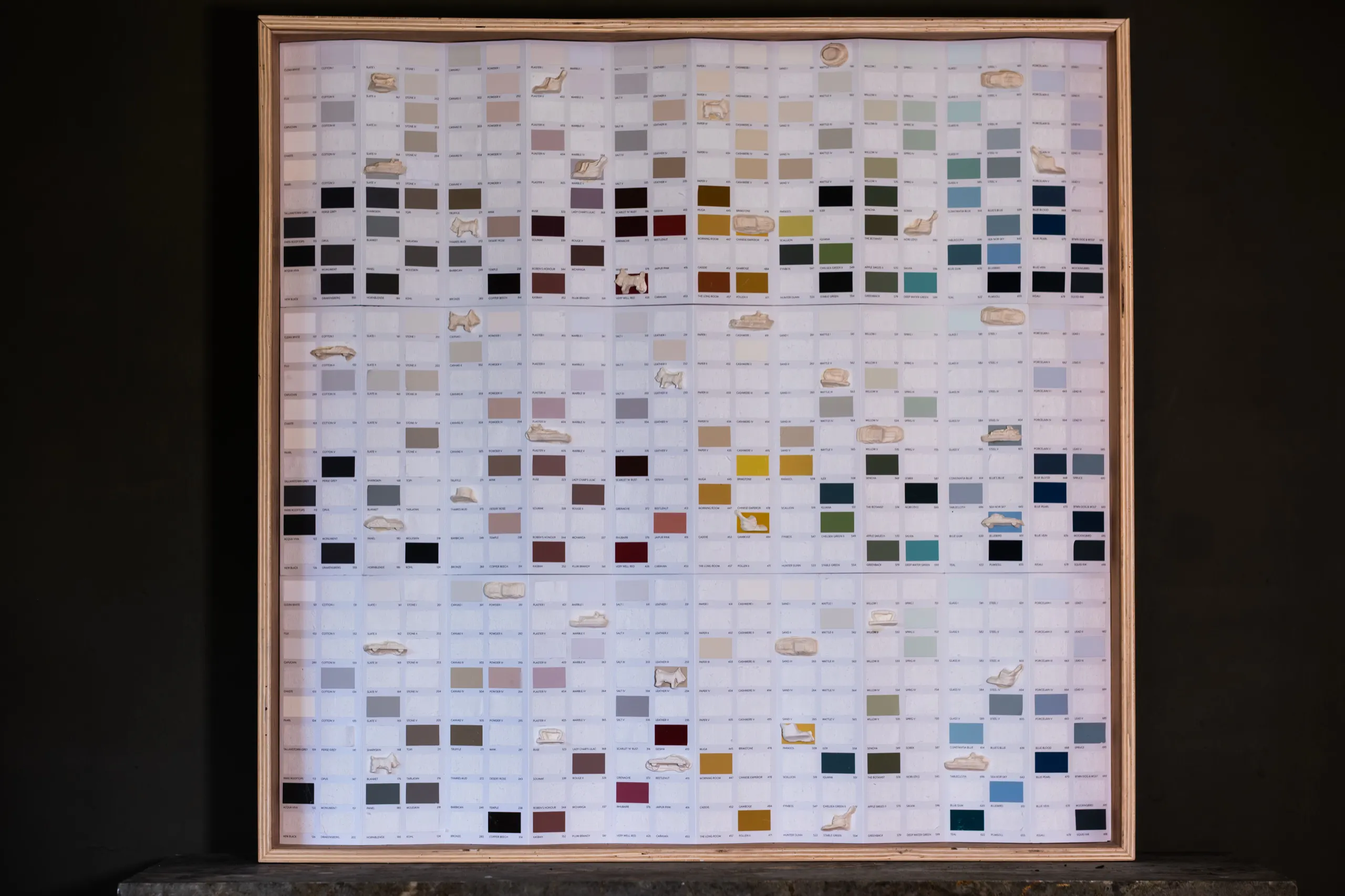A framed grid of paint colour chips set with cast Monopoly tokens