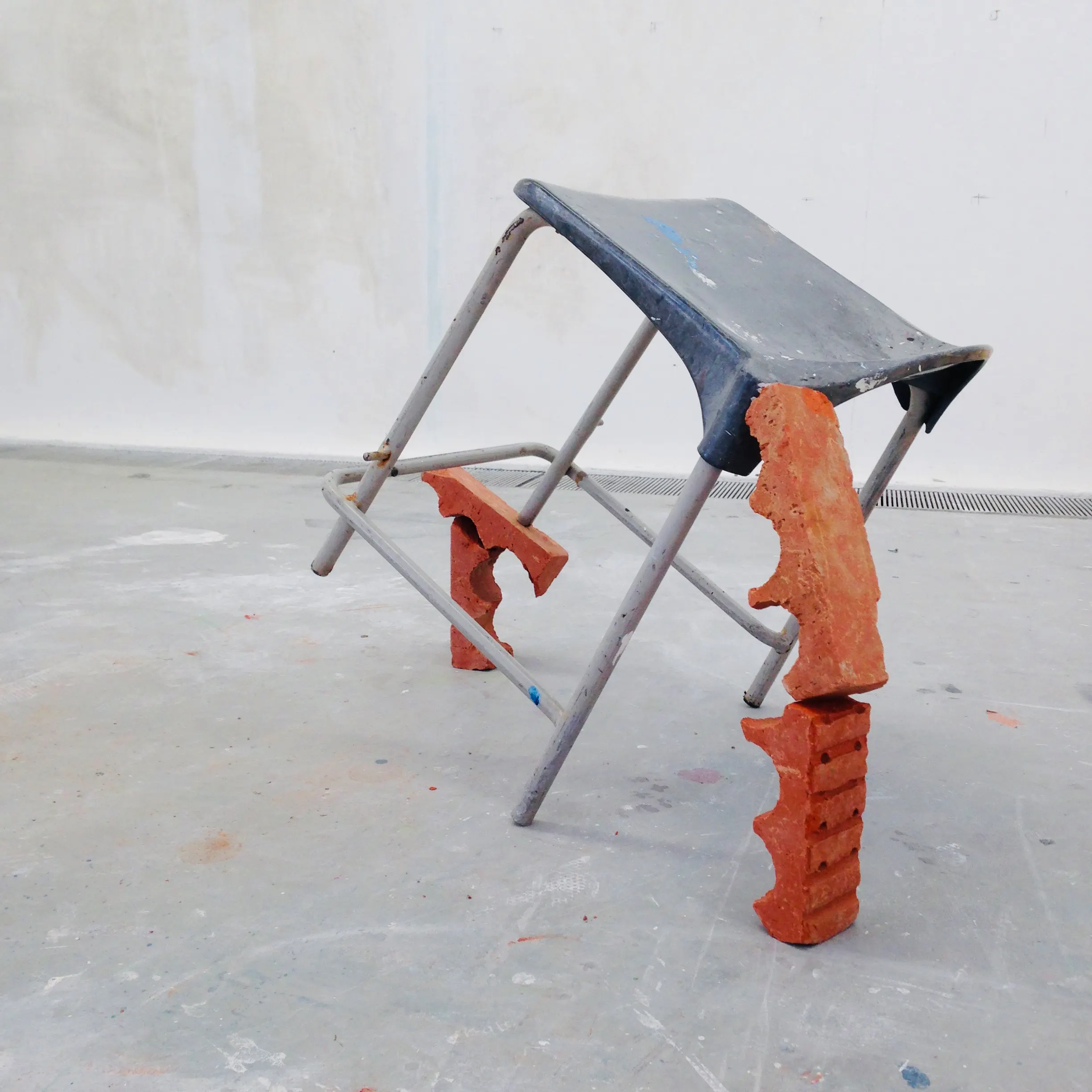 A folding stool propped on columns of brick