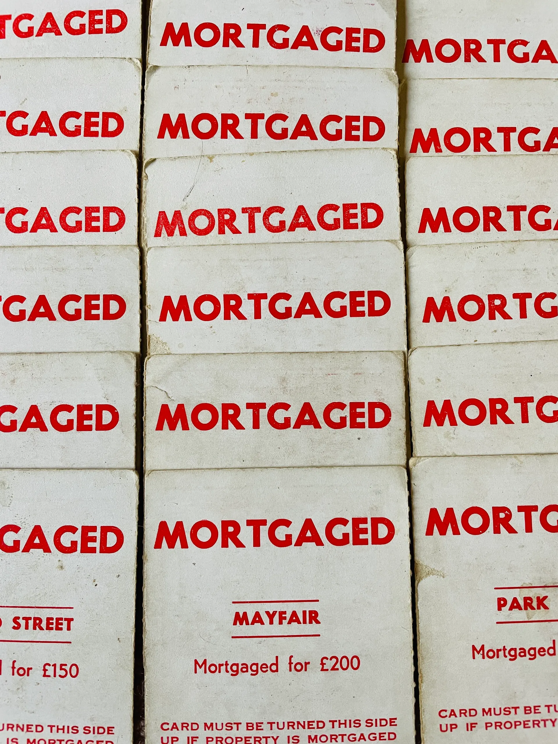 Rows of vintage Monopoly title deeds stamped MORTGAGED
