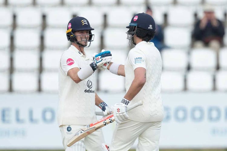 two cricket players shaking hands