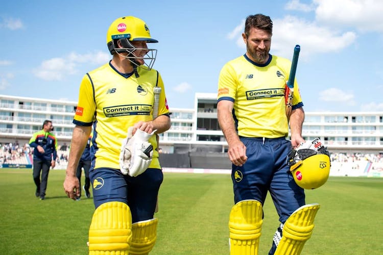 two cricket players walking on pitch