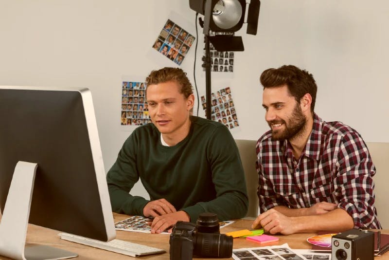 two men in front of a computer with video templates