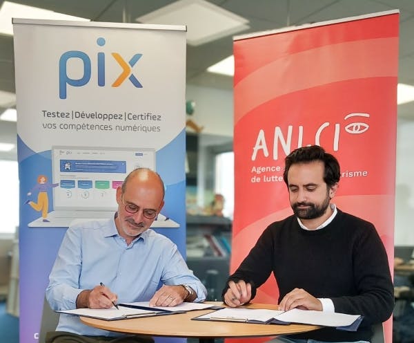 Assis à une table devant deux kakemonos, Hervé Fernandez (Directeur de l’ANLCI) et Benjamin Marteau (Directeur de Pix) signent la convention de partenariat dans les locaux de Pix.