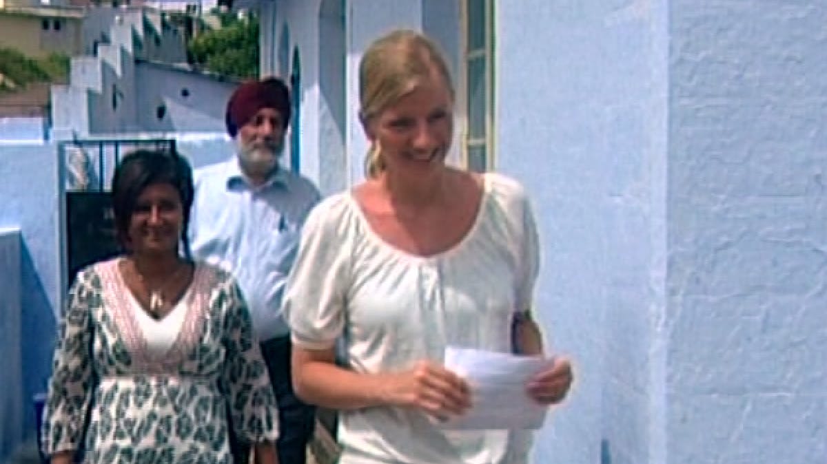 Three people walking in front of a white wall 