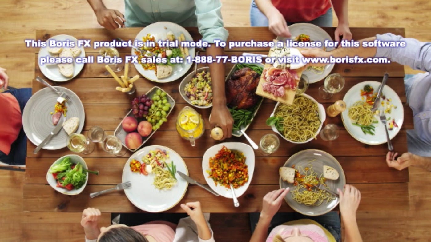 Image of dinner table with  people reaching for array of different dishes. 