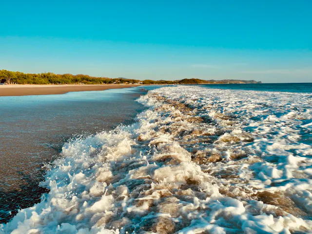 a view of a beach with waves coming in to shore