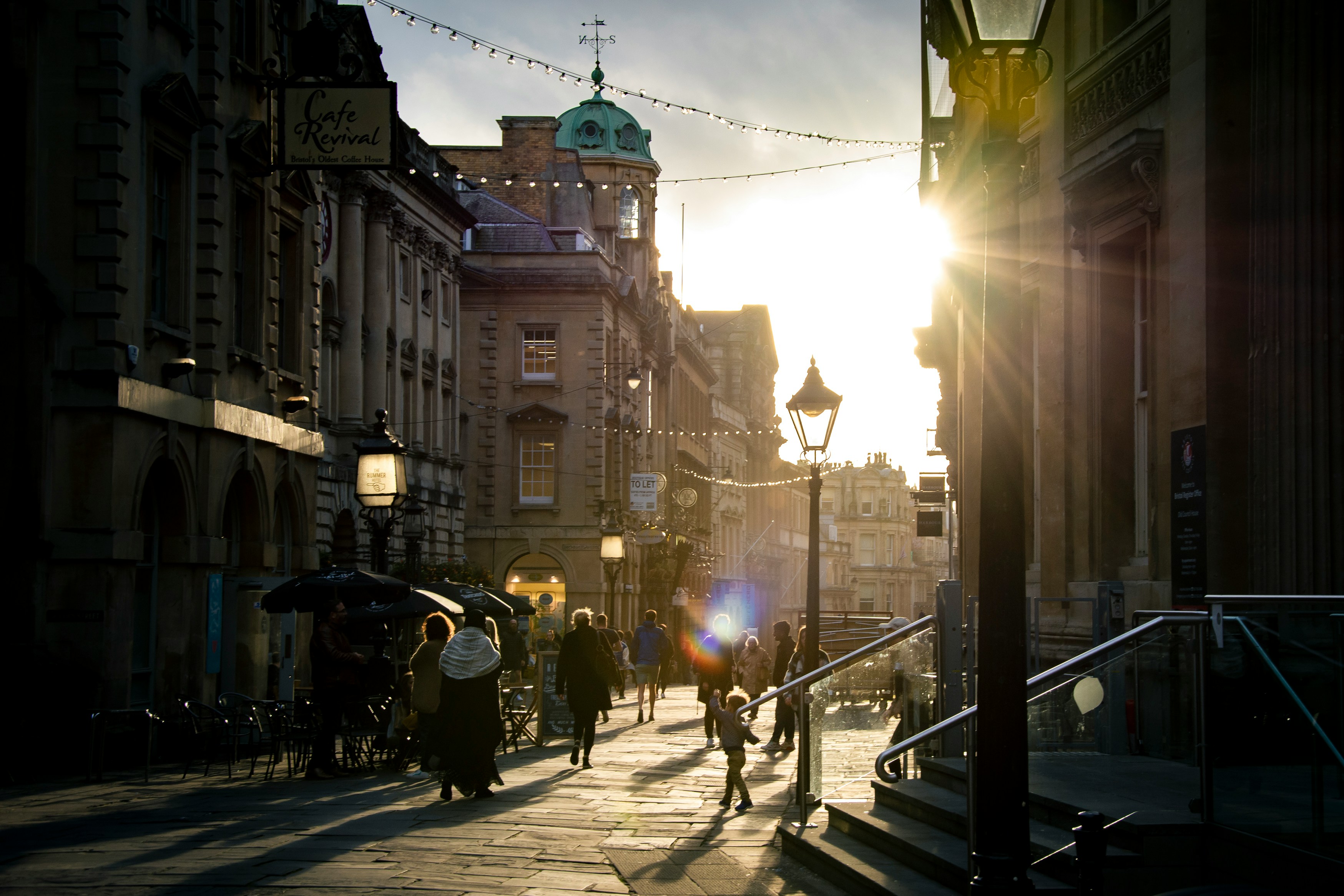 Pedestrians walking down a city street between tall residential and commercial buildings