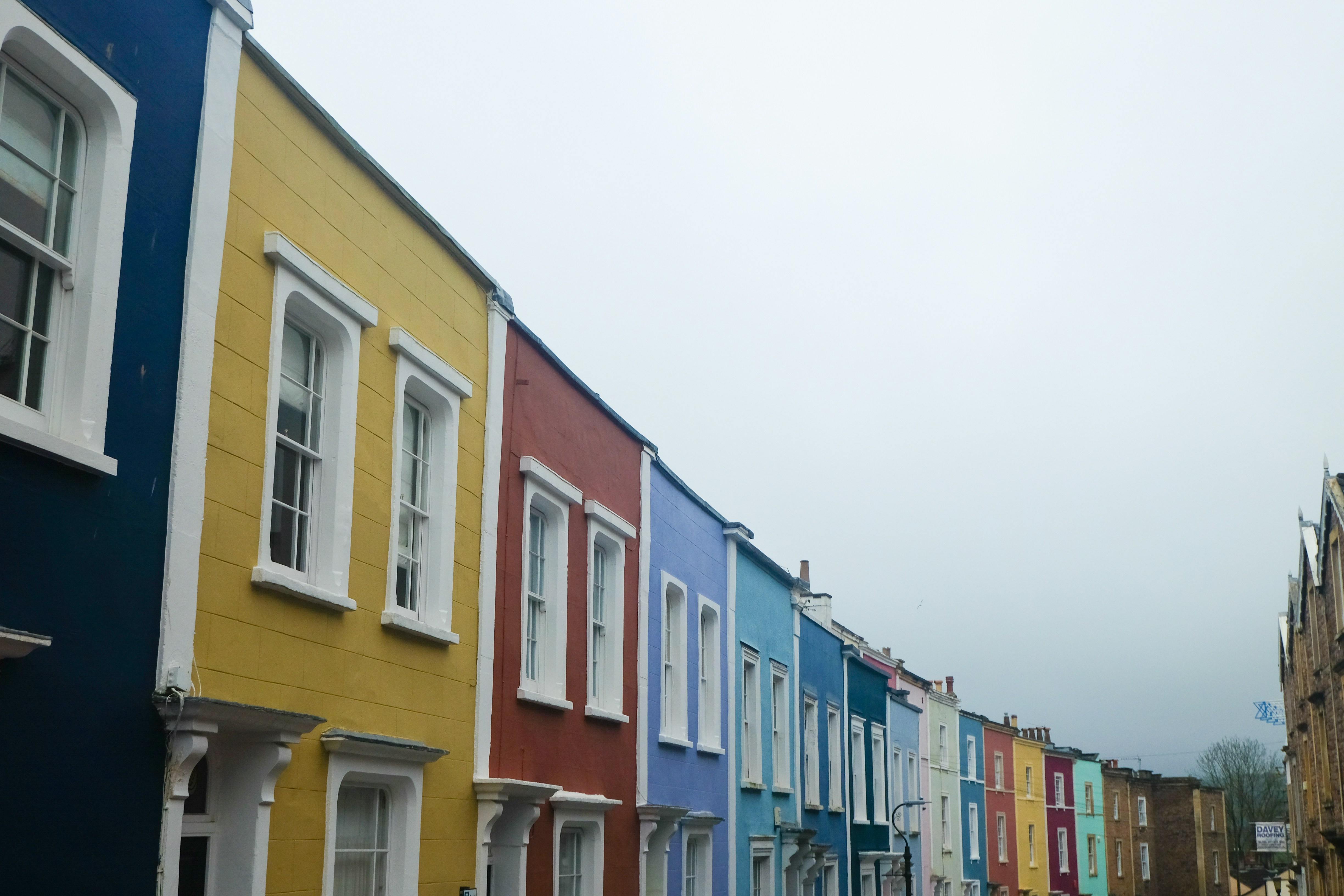 Row of colourful terraced houses painted blue, yellow, red and turquoise on a residential street